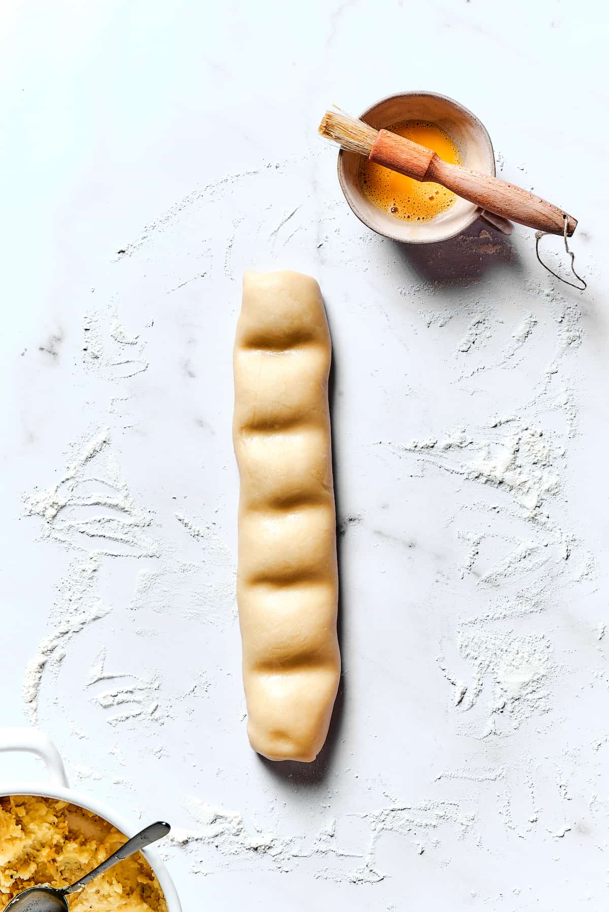 Potato Knishes are a popular Jewish recipe featuring a mashed potato and onion filling wrapped in a thin, flaky dough and baked to golden. A roll of dough that's been sectioned into rectangles