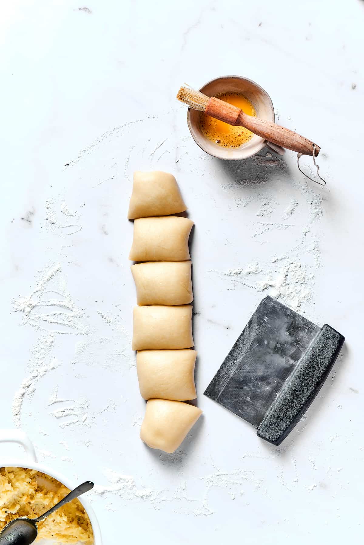 Potato Knishes are a popular Jewish recipe featuring a mashed potato and onion filling wrapped in a thin, flaky dough and baked to golden. Dough stuffed with mashed potatoes that's been cut into squares