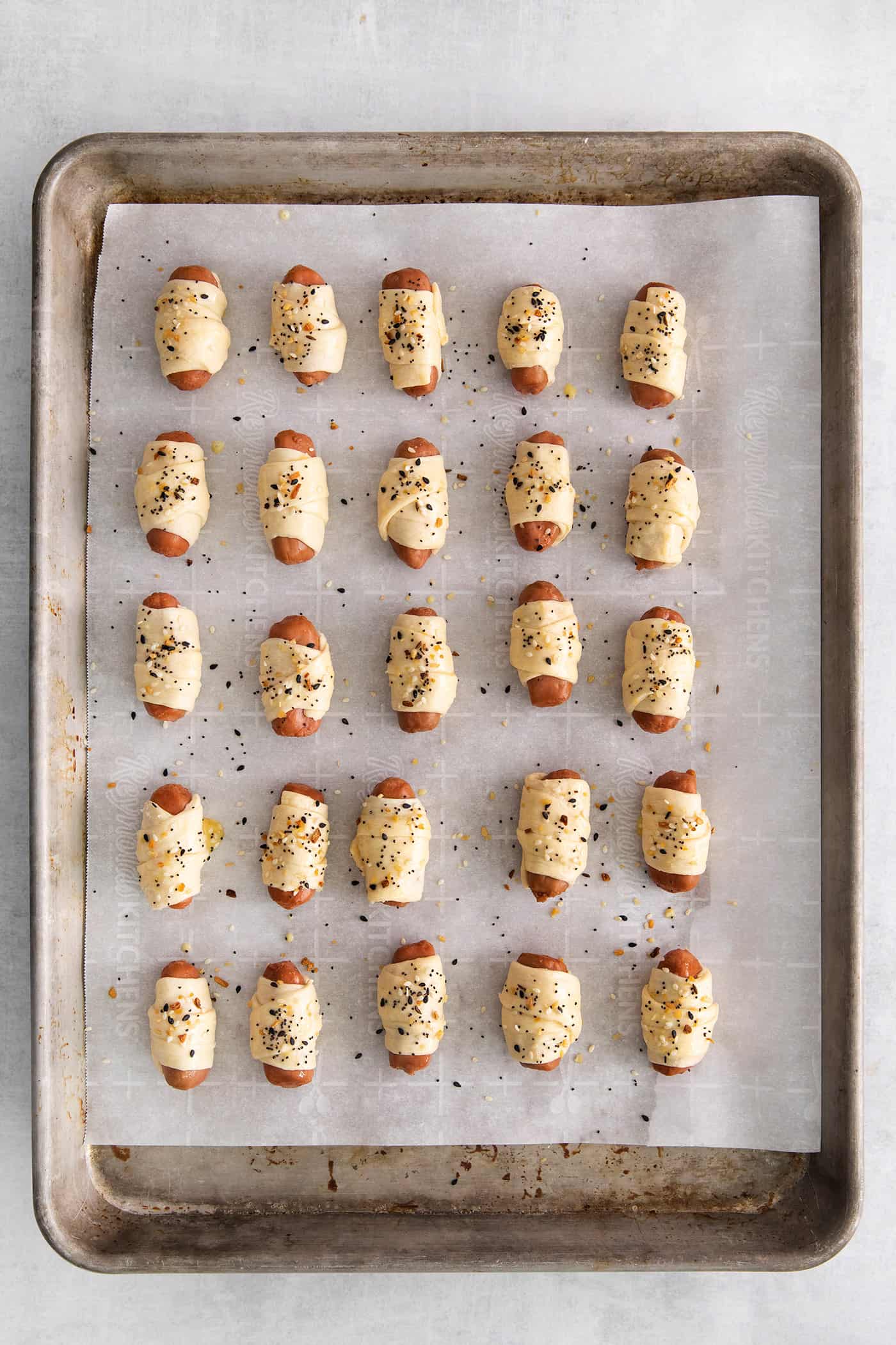 Everything Bagel Pigs in a Blanket are the perfect appetizer– mini sausage wrapped in crescent dough, topped with everything bagel seasoning Overhead view of mini sausages wrapped in crescent dough and topped with everything bagel seasoning