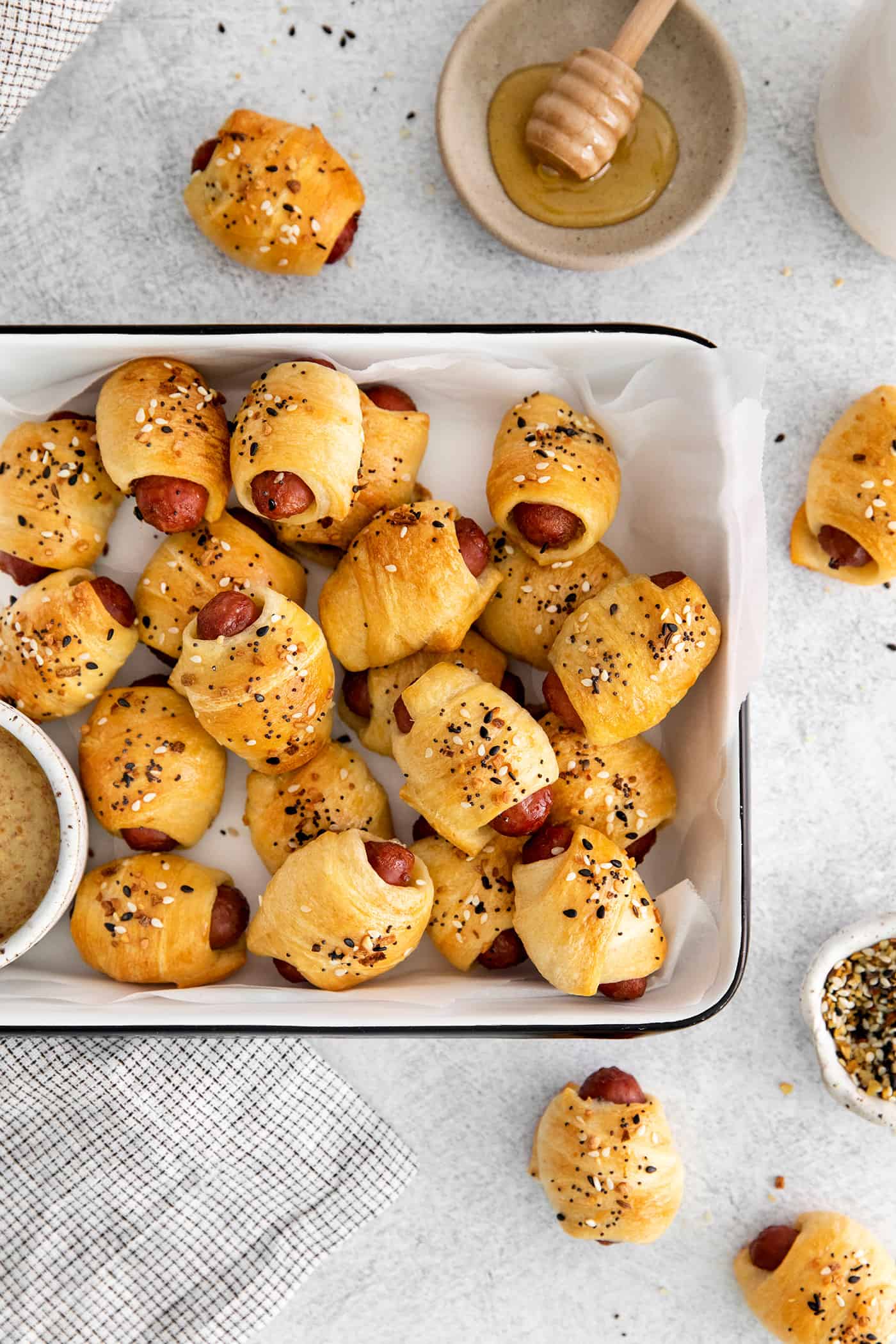 Everything Bagel Pigs in a Blanket are the perfect appetizer– mini sausage wrapped in crescent dough, topped with everything bagel seasoning A serving tray of mini everything bagel pigs in a blanket