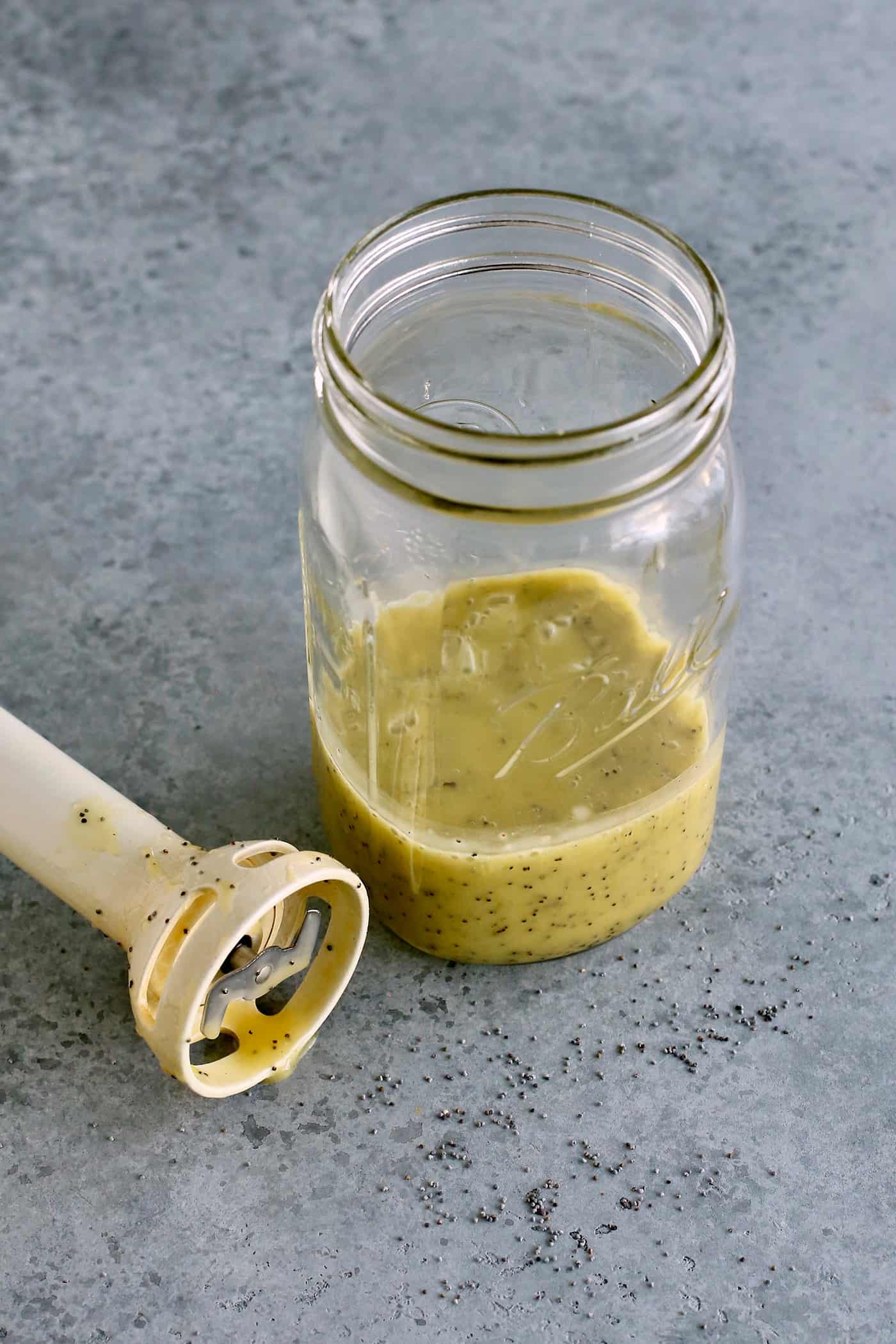 A quick & easy homemade poppy seed dressing with bright lemon flavor and a light, creamy consistency. It's versatile, fresh, and delicious! a jar of poppy seed dressing and an immersion blender