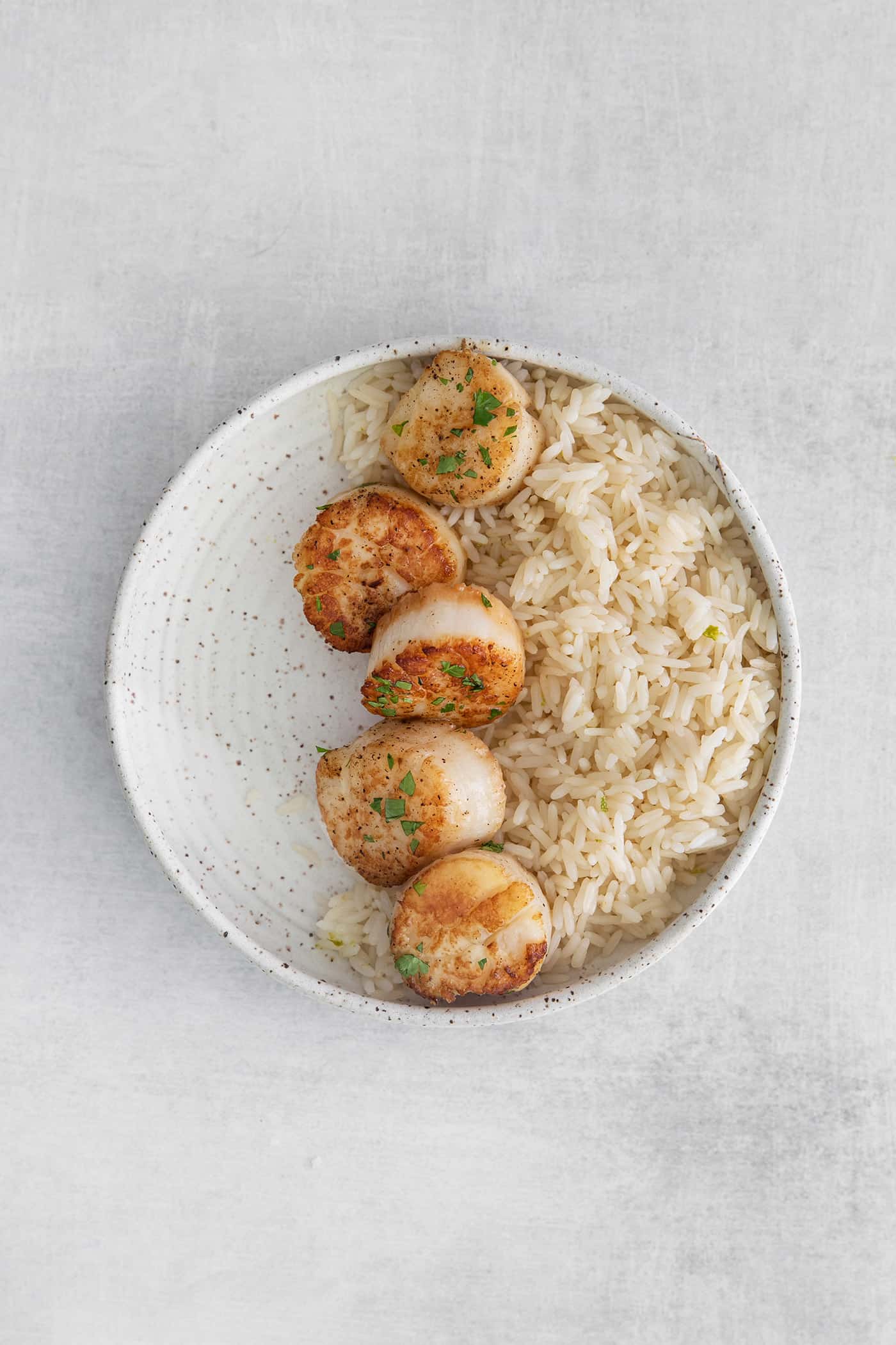 These Tex-Mex Scallop Rice Bowls are bright, refreshing, and packed with flavor, with scallops, pico de gallo, and lime crema. Seared scallops and rice in a bowl