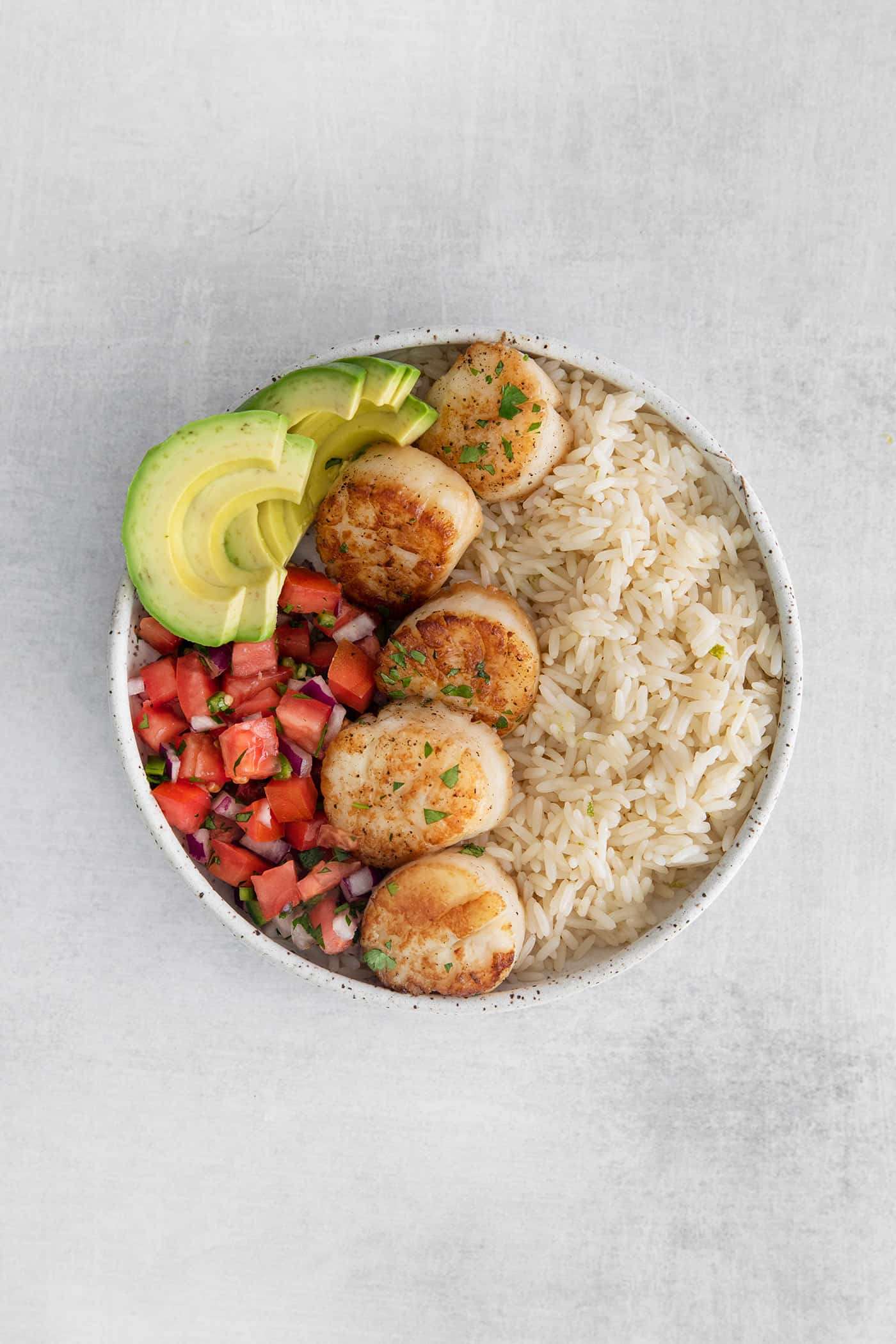 These Tex-Mex Scallop Rice Bowls are bright, refreshing, and packed with flavor, with scallops, pico de gallo, and lime crema. Overhead view of a scallop rice bowl