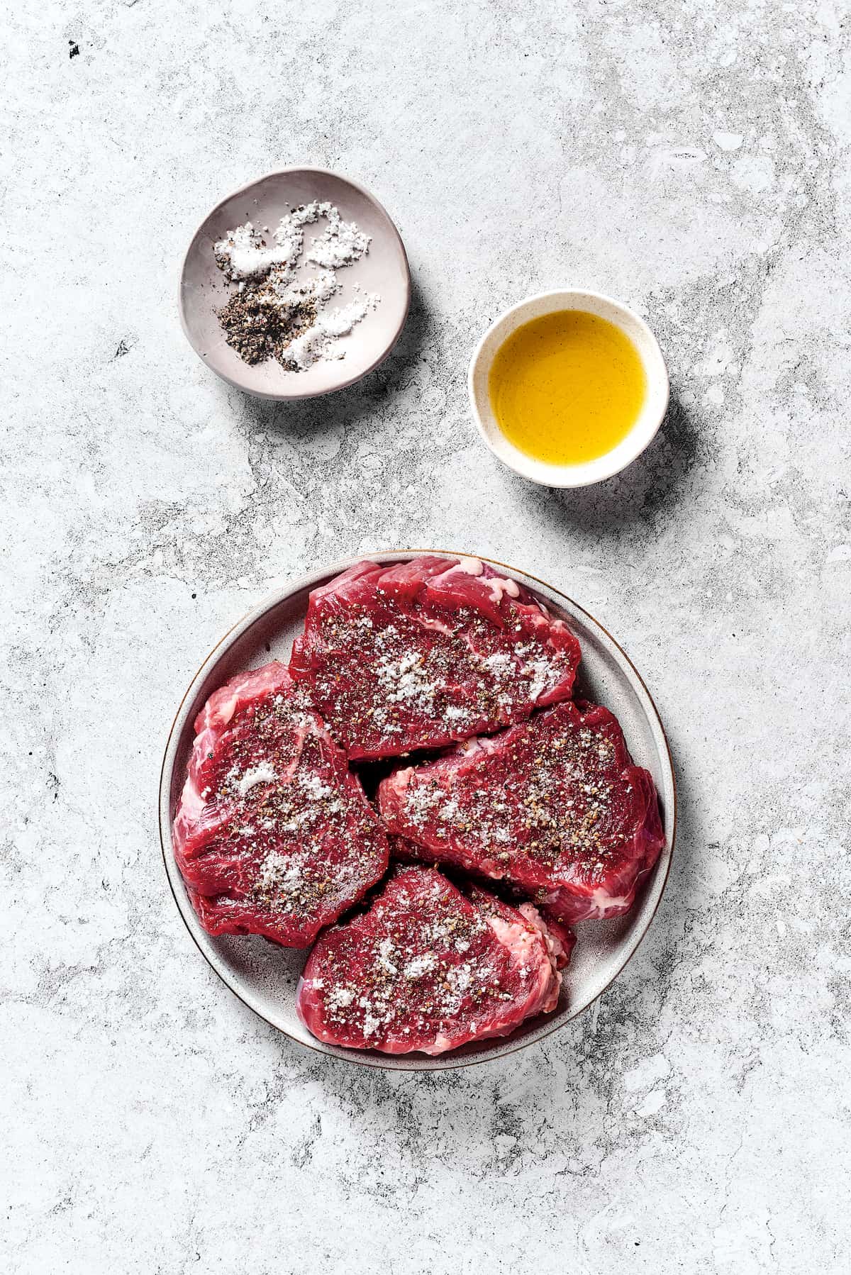 Steak Diane is a classic beef tenderloin recipe with pan-cooked steak in a creamy mushroom sauce. Simple but elegant & ready in 45 minutes. Beef tenderloin seasoned with salt and pepper on a plate