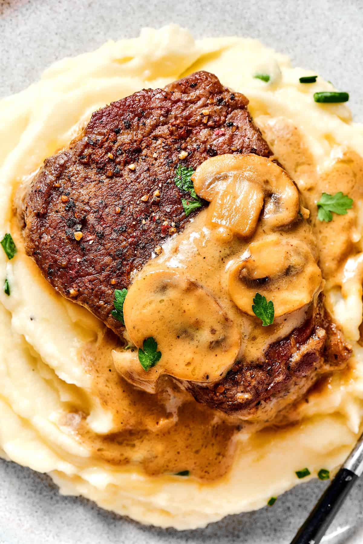 Steak Diane is a classic beef tenderloin recipe with pan-cooked steak in a creamy mushroom sauce. Simple but elegant & ready in 45 minutes. Overhead view of Steak diane over buttermilk mashed potatoes