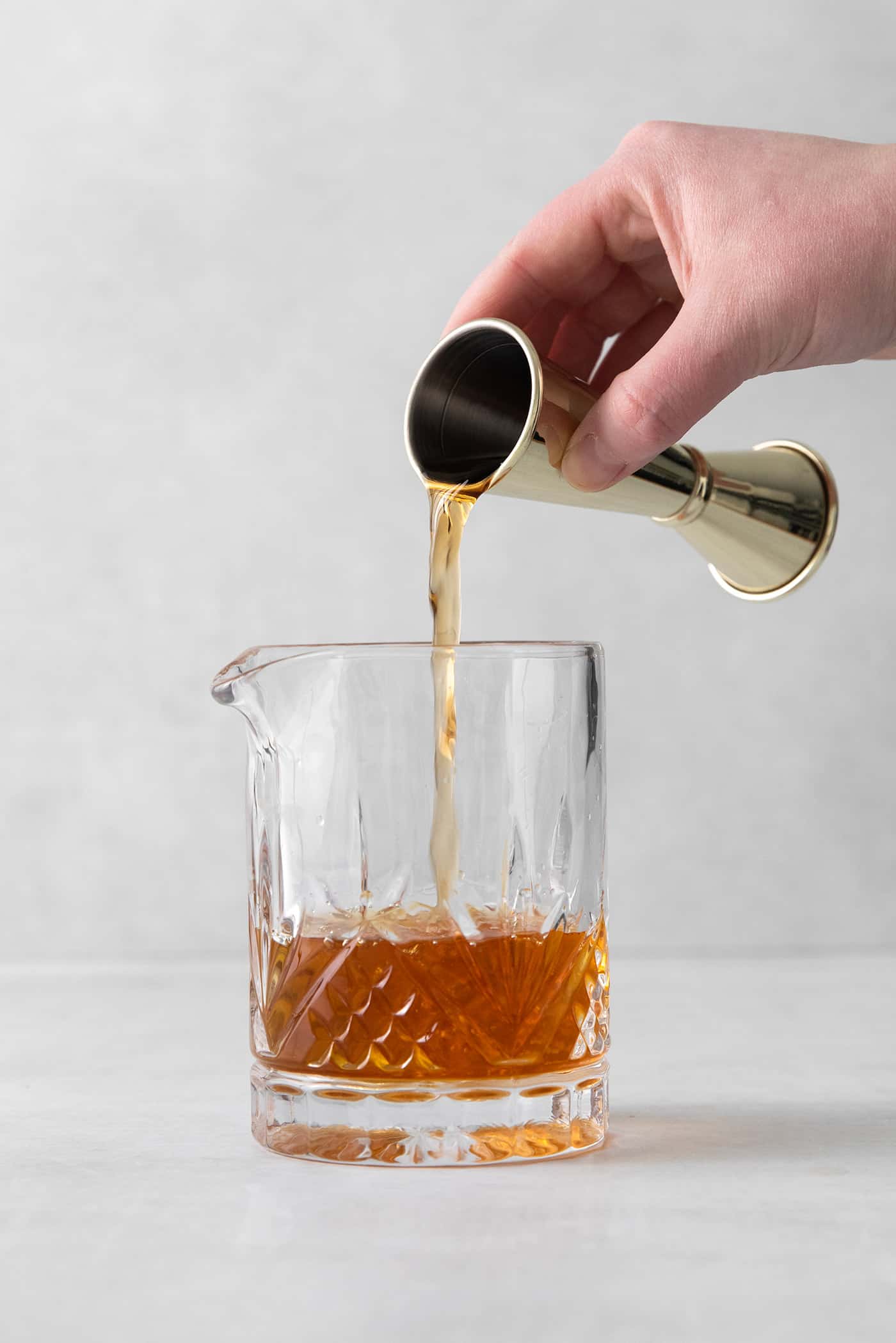 This classic Manhattan is a strong and earthy cocktail with just a hint of sweetness. Fancy and elegant, with 3 ingredients. A hand pouring bourbon into a glass