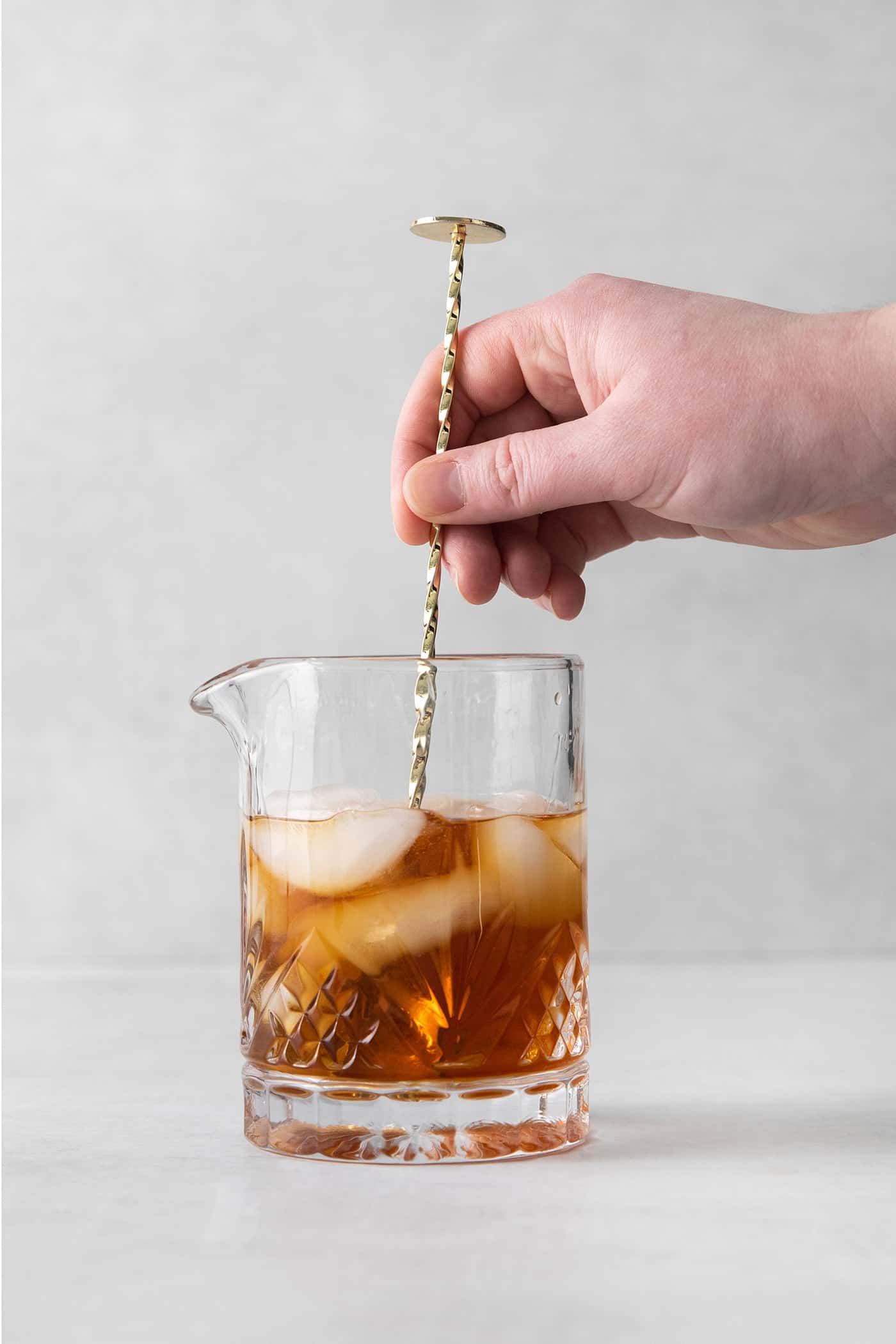 This classic Manhattan is a strong and earthy cocktail with just a hint of sweetness. Fancy and elegant, with 3 ingredients. A spoon stirring a cocktail