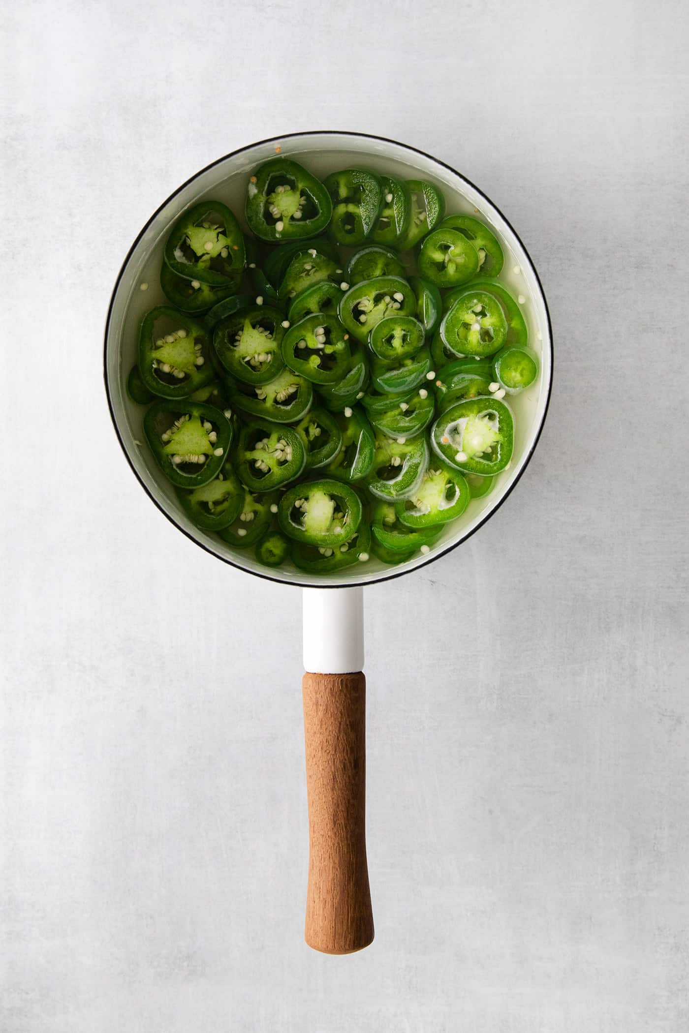 With just 5 ingredients, these Pickled Jalapenos are spicy and tangy. Add them to sandwiches and salads or straight from the jar. Overhead view of a saucepan of jalapenos