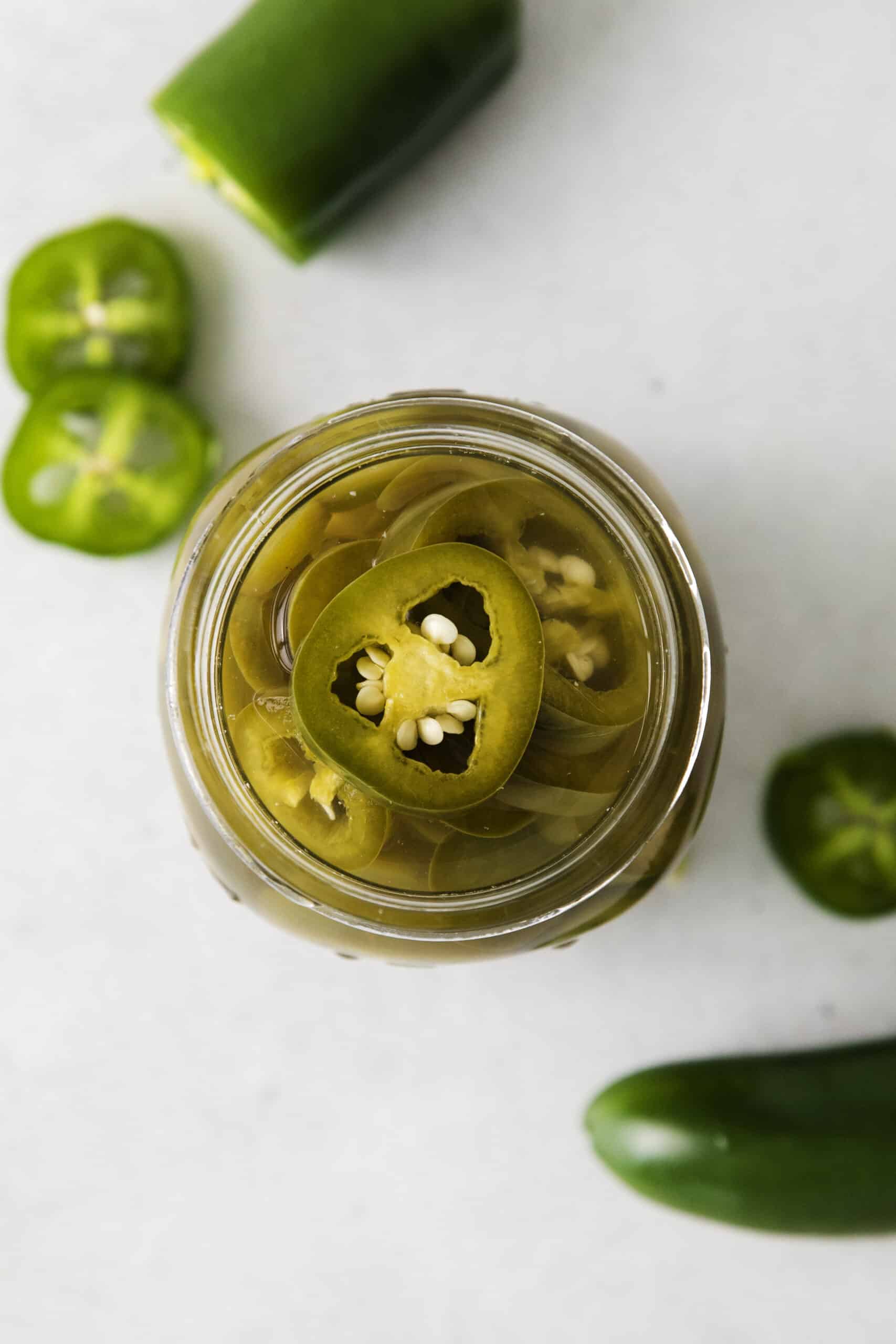 With just 5 ingredients, these Pickled Jalapenos are spicy and tangy. Add them to sandwiches and salads or straight from the jar. Overhead view of a jar of jalapenos