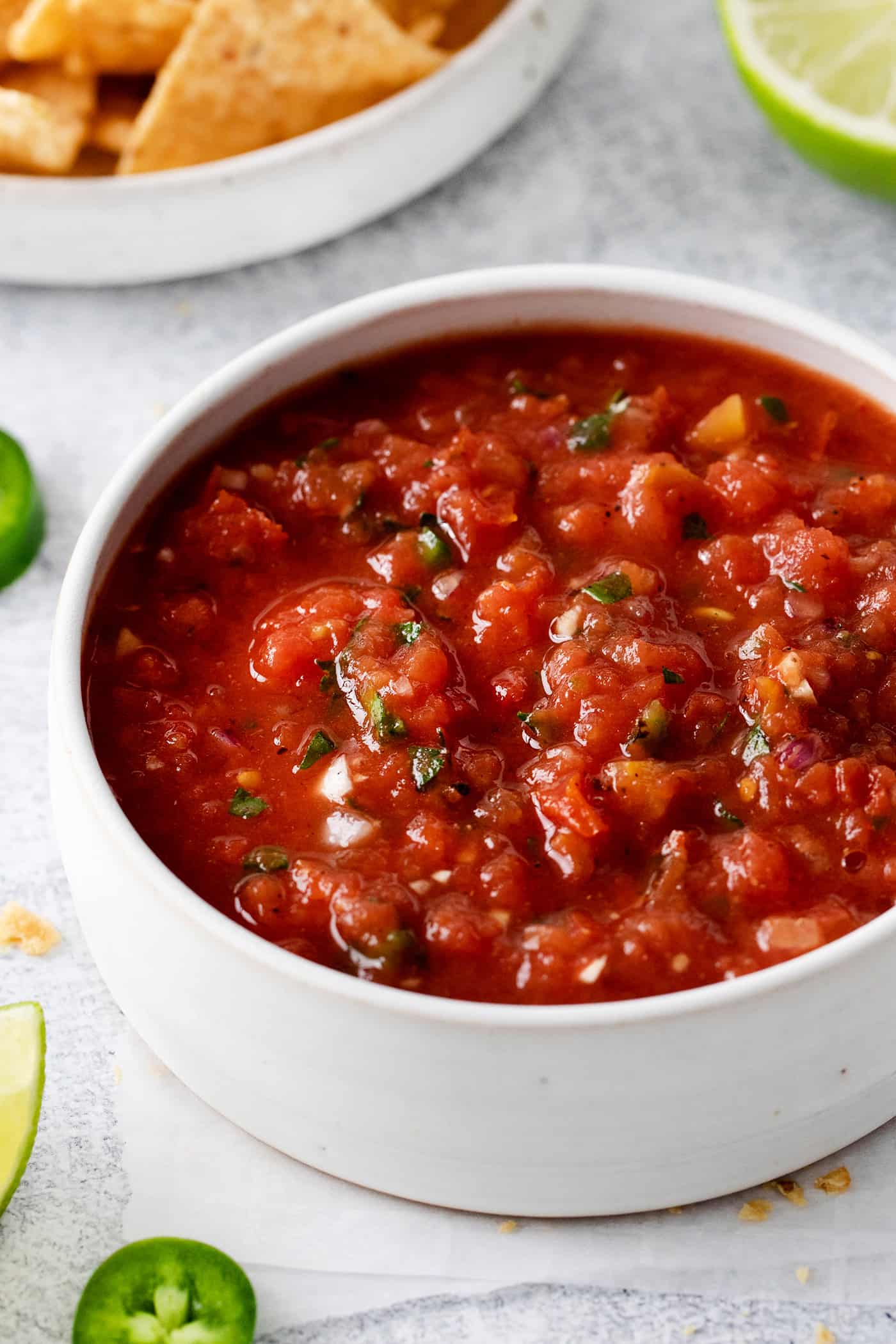 This Restaurant Style Salsa is a mild and easy salsa recipe made with fire-roasted tomatoes, jalapenos, cilantro, and Iime. A white bowl of authentic Mexican salsa