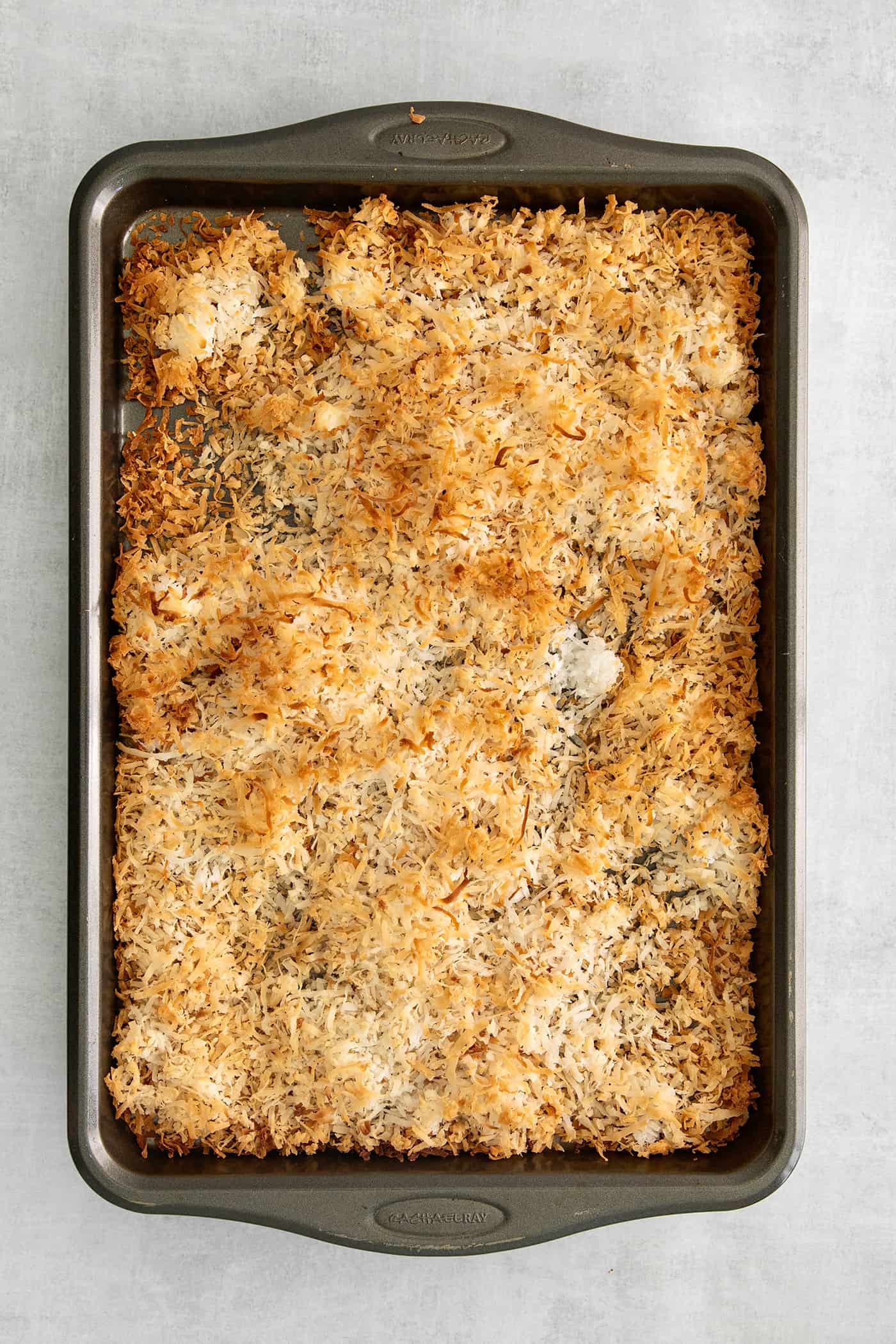 These Samoa Macaroons are rich and nutty, made with toasted coconut and dulce de leche and then dipped in chocolate. Toasted coconut on a baking sheet