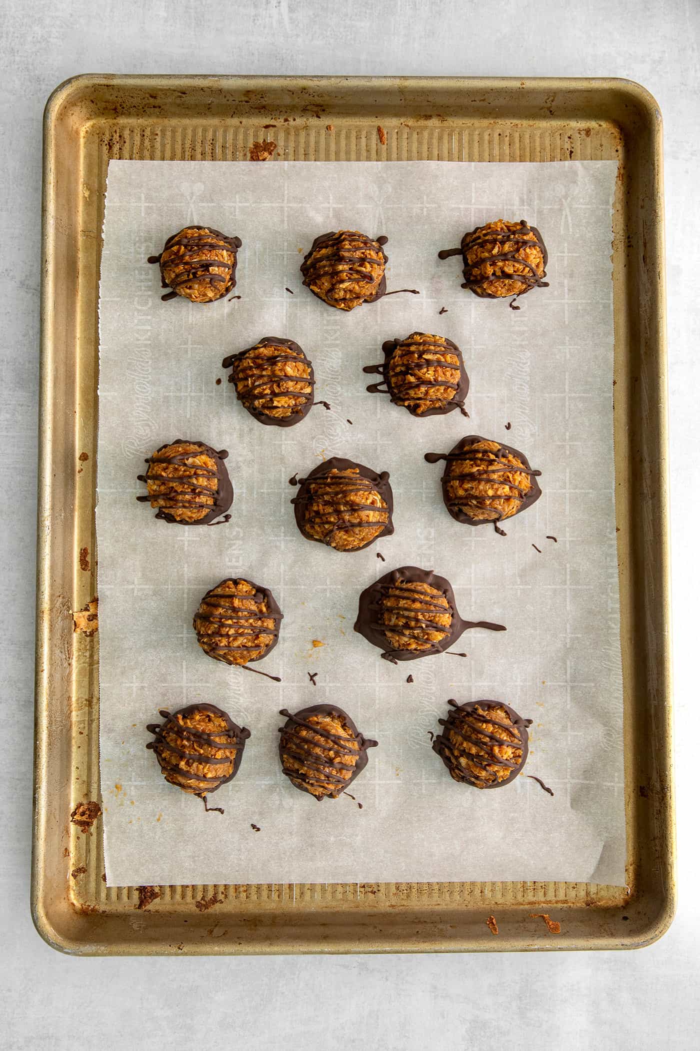 These Samoa Macaroons are rich and nutty, made with toasted coconut and dulce de leche and then dipped in chocolate. Chocolate dipped dulce de leche macaroons on a baking sheet
