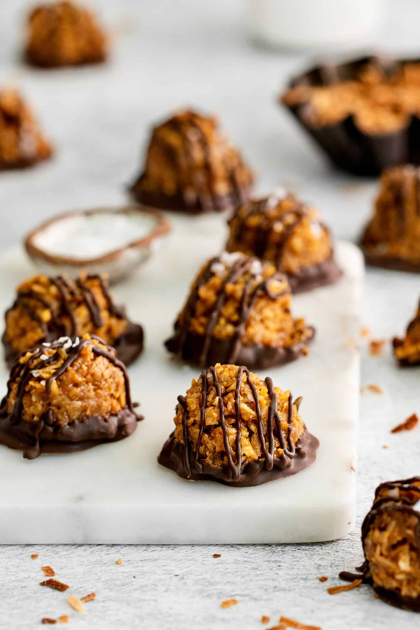 These Samoa Macaroons are rich and nutty, made with toasted coconut and dulce de leche and then dipped in chocolate. Dulce de leche macaroons on a cutting board
