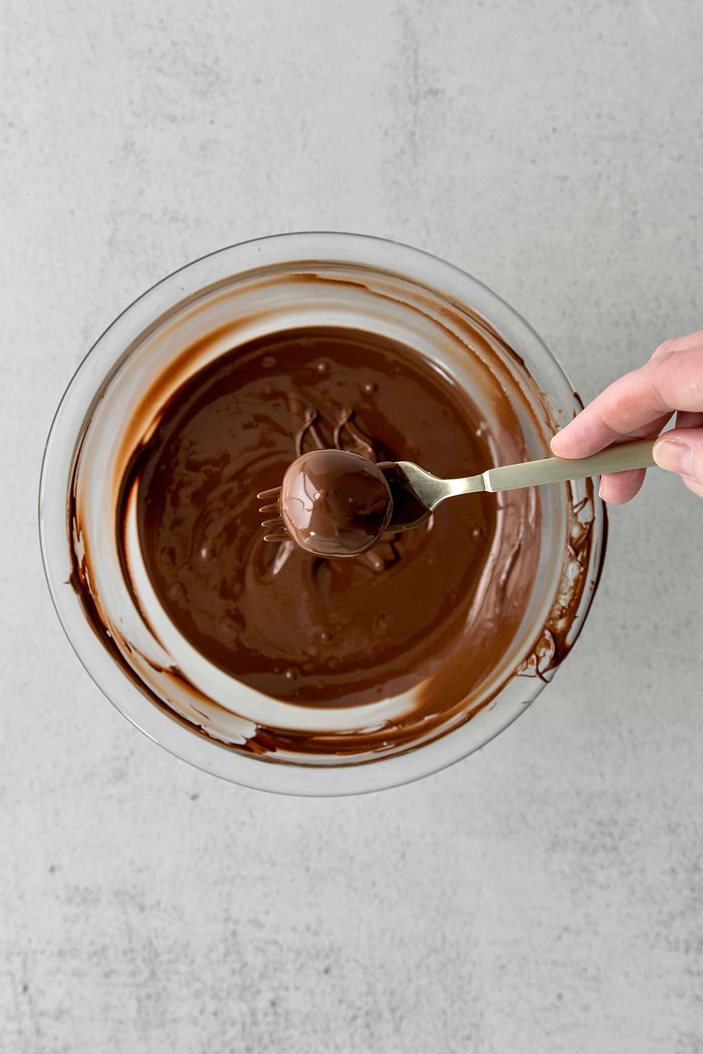 Made with your favorite Girl Scout cookies, these Thin Mint Truffles are the perfect combination of rich chocolate and mint flavor. A truffle on a fork above a bowl of melted chocolate