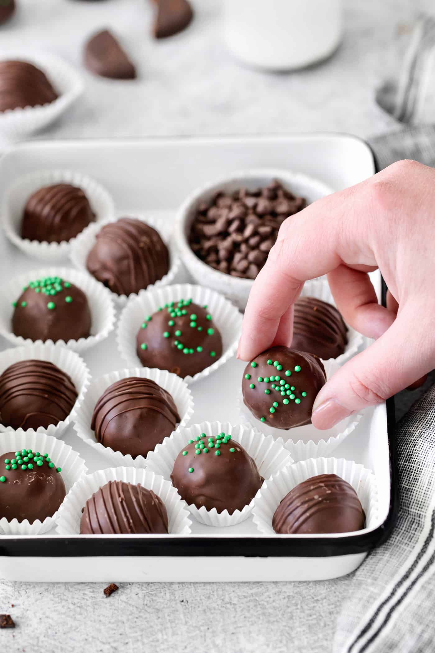 Made with your favorite Girl Scout cookies, these Thin Mint Truffles are the perfect combination of rich chocolate and mint flavor. A hand grabbing a chocolate truffle