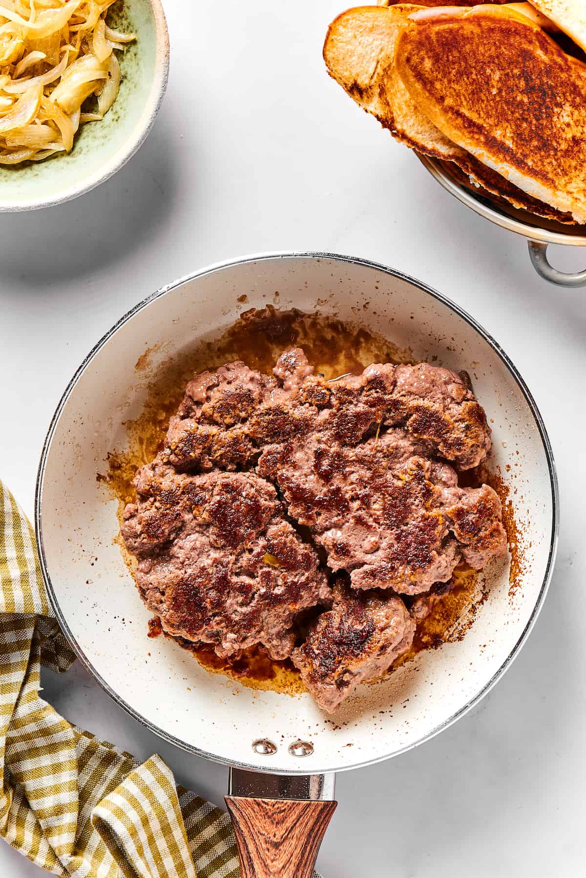 With ground beef, sauteed onions, and LOTS of cheese, it's easy to see why this Chopped Cheese Sandwich is always a hit! A large patty of ground beef in a frying pan