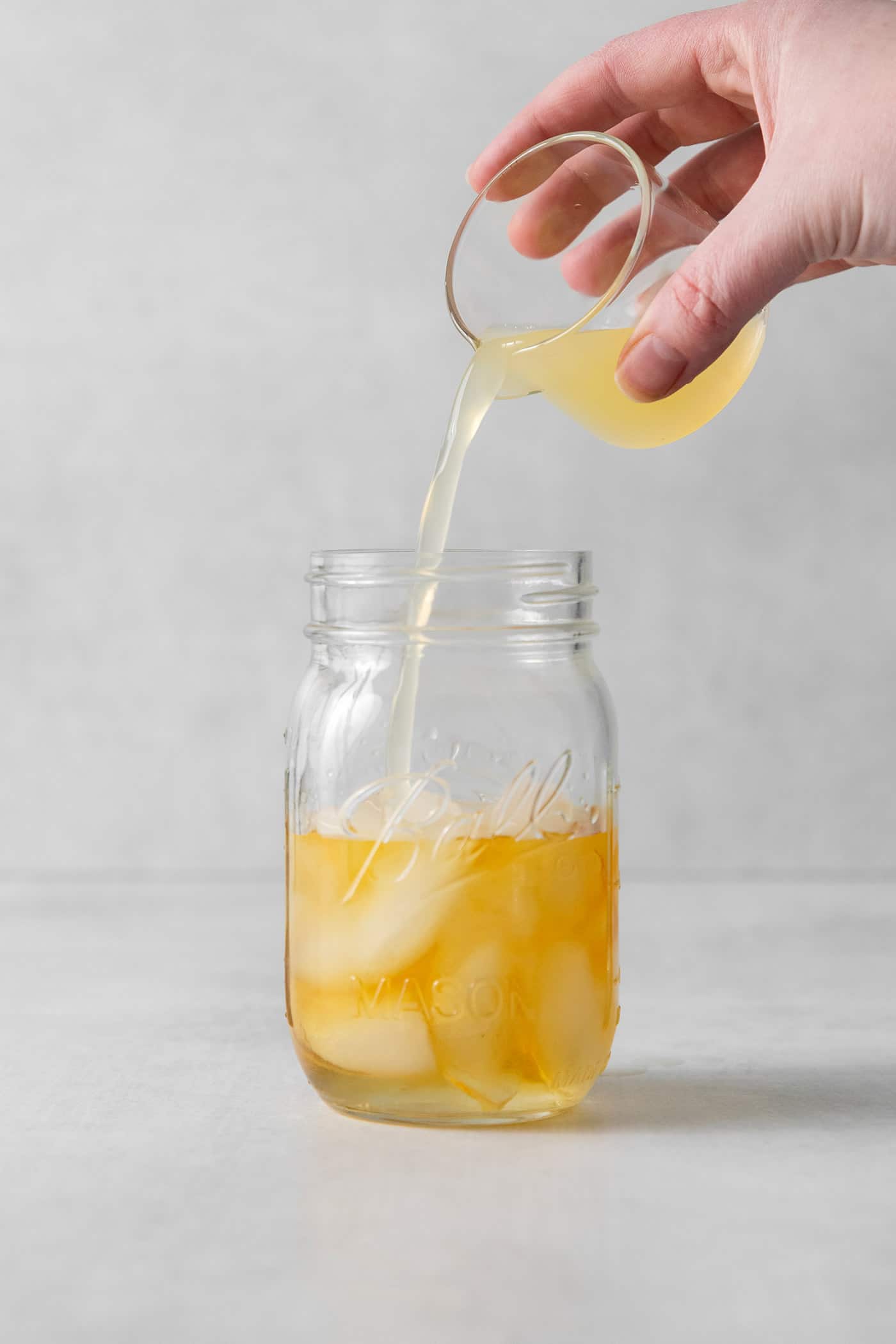 This New York Sour is made with whiskey, freshly squeezed lemon juice, simple syrup, and fruity red wine. Perfectly sweet & tart. Lemon juice being poured into a mason jar with whiskey