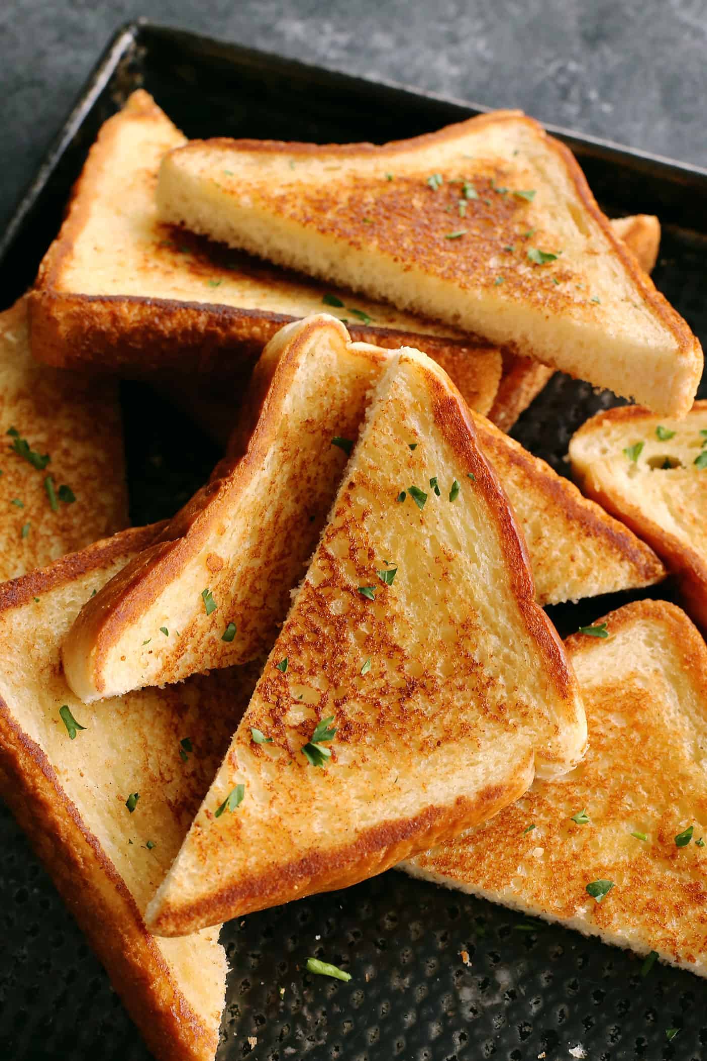 This Homemade Texas Toast Garlic Bread is made entirely on the stovetop with just 3 ingredients. It's the perfect addition to any meal. Overhead view of slices of Texas Toast garlic bread