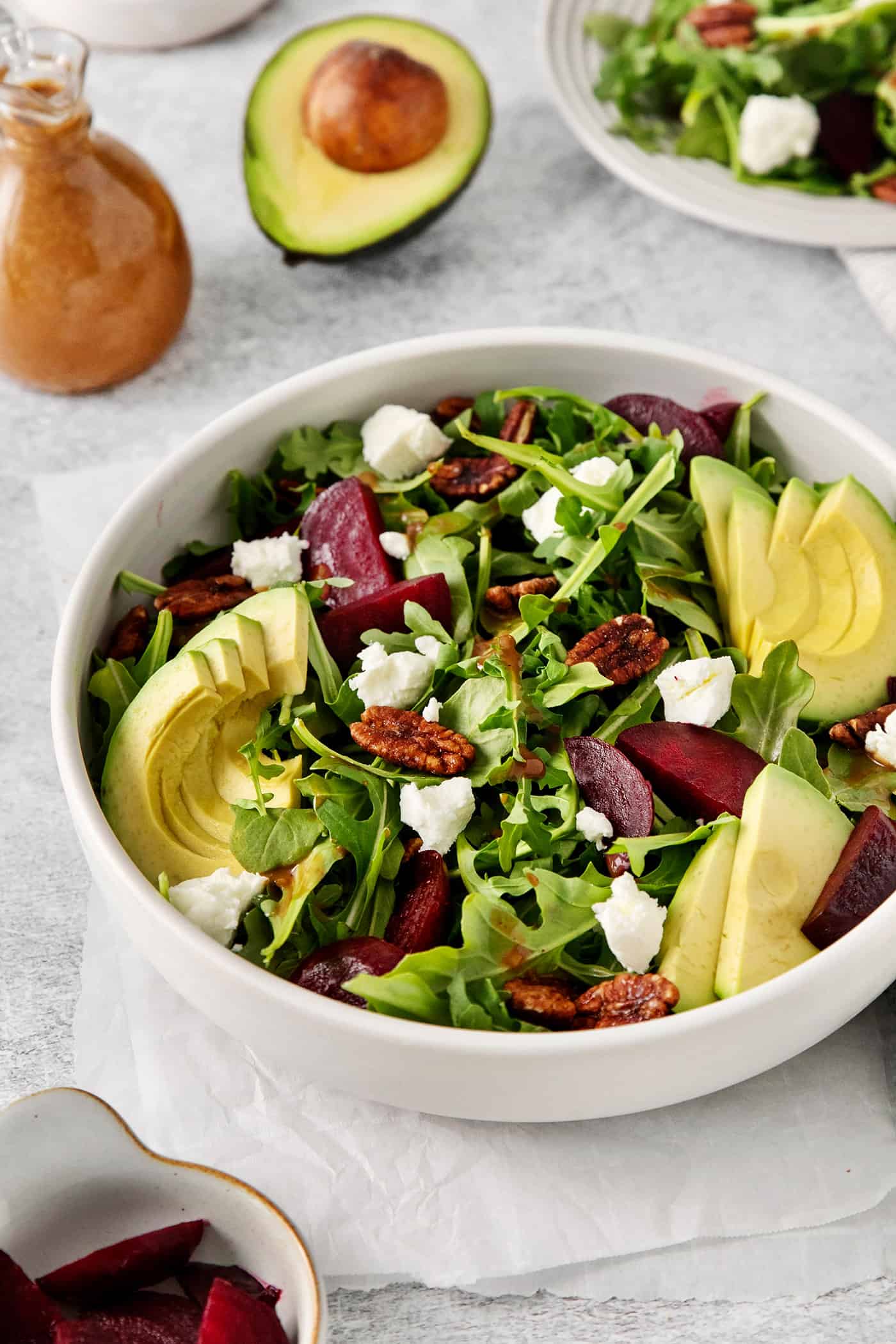 Topped with goat cheese, avocado, and candied pecans, this Arugula Beet Salad offers the perfect combination of flavors. Angled view of a bowl of beet goat cheese salad
