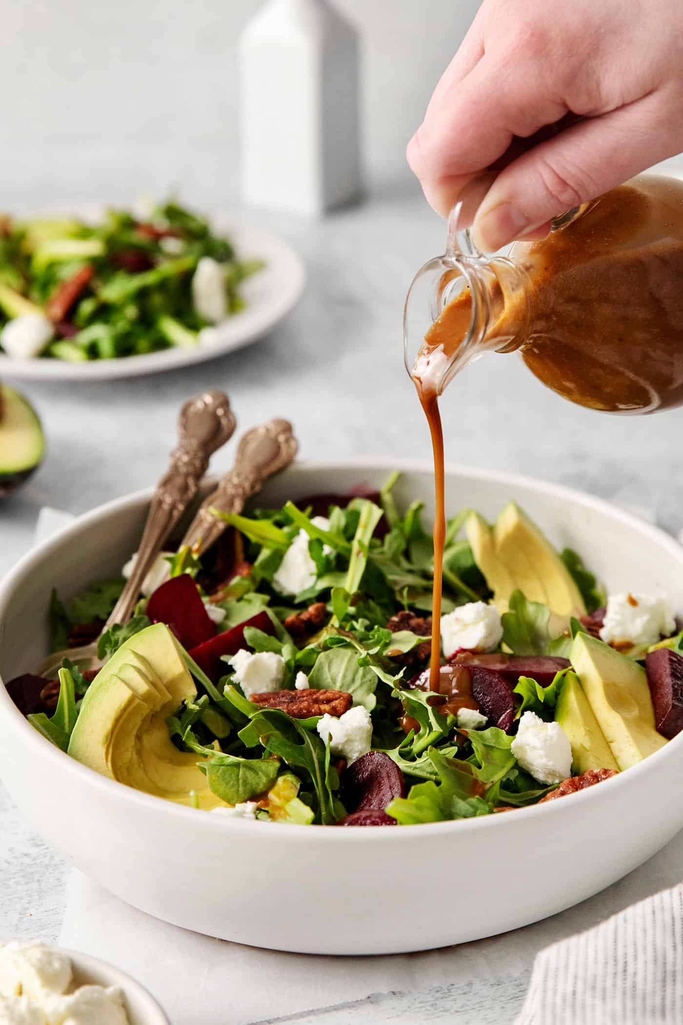 Topped with goat cheese, avocado, and candied pecans, this Arugula Beet Salad offers the perfect combination of flavors. Balsamic vinaigrette being poured over arugula salad