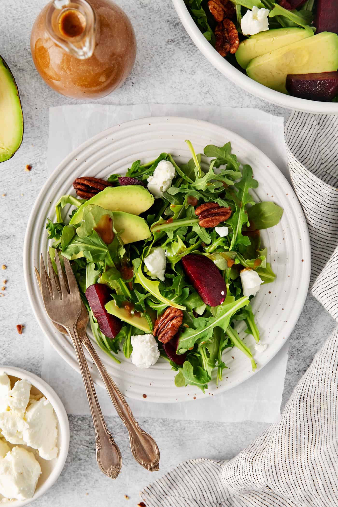 Topped with goat cheese, avocado, and candied pecans, this Arugula Beet Salad offers the perfect combination of flavors. Overhead view of a plate of arugula goat cheese salad