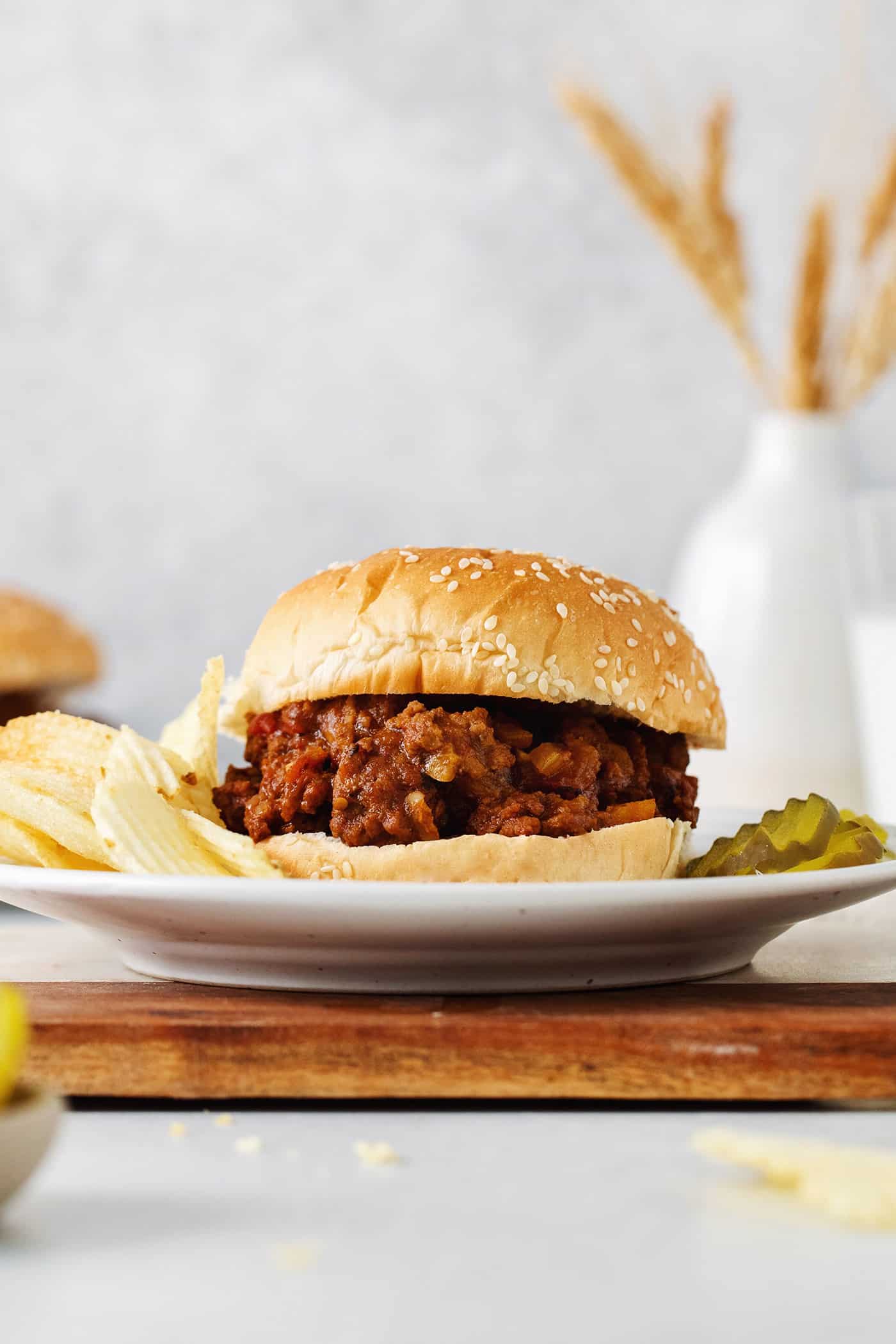 Slow Cooker Sloppy Joes are super flavorful, easy to make, and great for feeding a crowd. Serve on sandwich buns for a quick meal anytime. A sloppy joe sandwich on a plate with chips and pickles