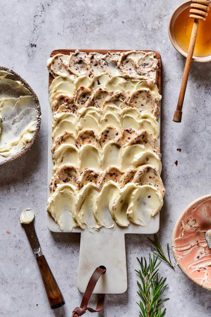 This Butter Board with Bacon Butter features toppings like dried fruits, nuts, and honey for an easy, savory butter charcuterie board. Salted butter and bacon butter spread on a wooden cutting board