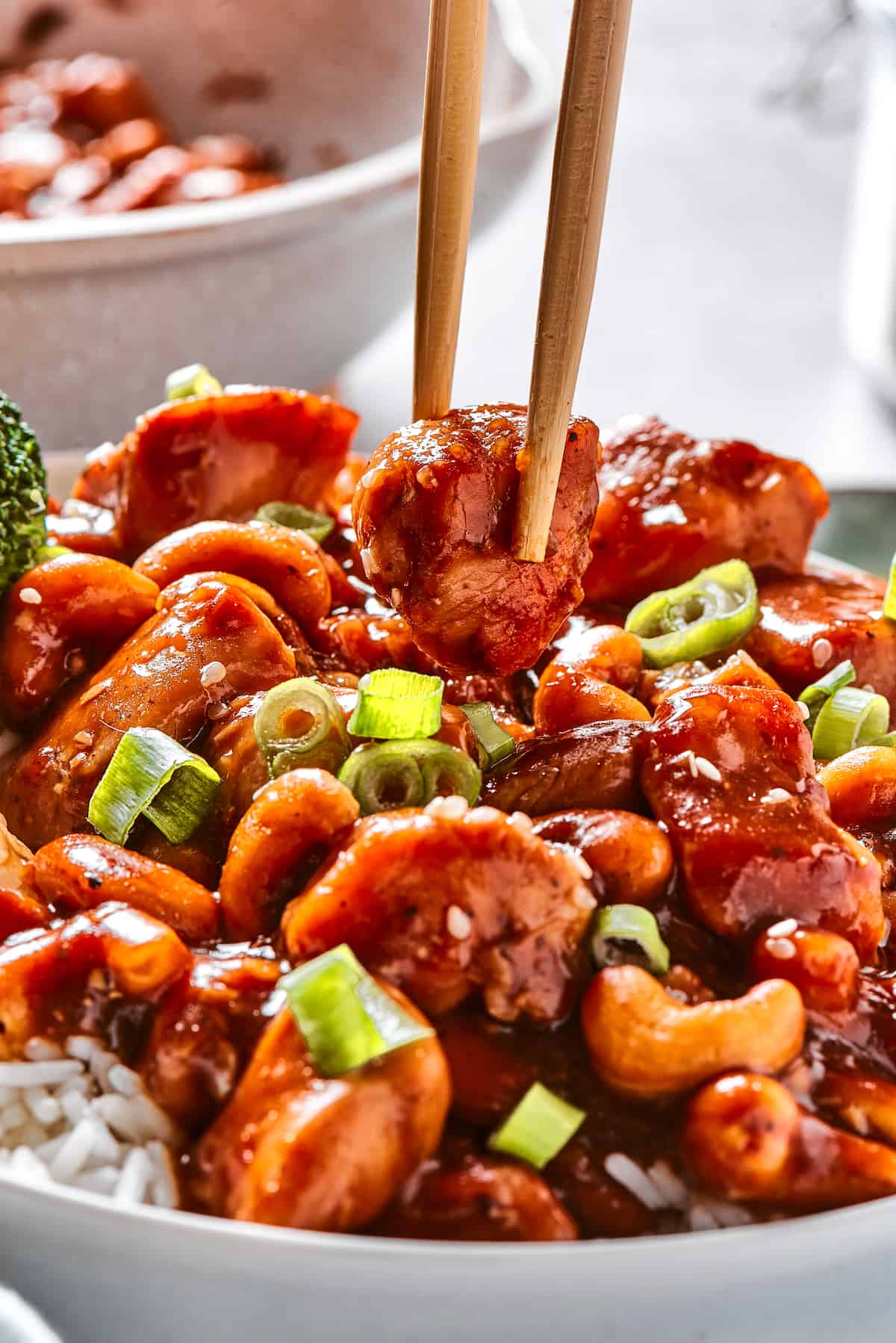 Quick, easy, and so flavorful, this Cashew Chicken stir fry features juicy pieces of chicken breast and cashews tossed in a garlic sauce. A piece of cashew chicken in chopsticks