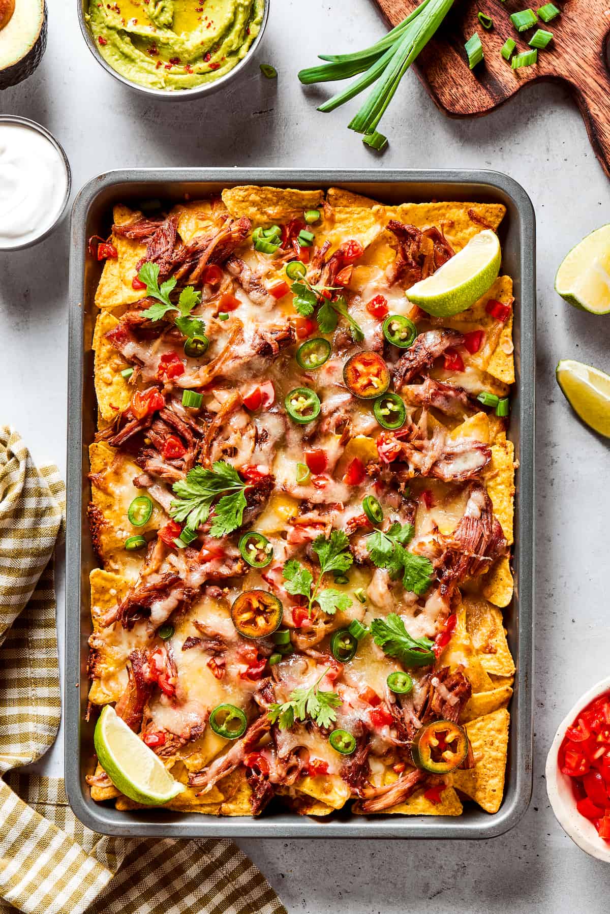 Loaded with pork, cheese, tomatoes, and all the toppings you desire, these Pulled Pork Nachos are an easy and tasty appetizer. Overhead view of pulled pork baked nachos