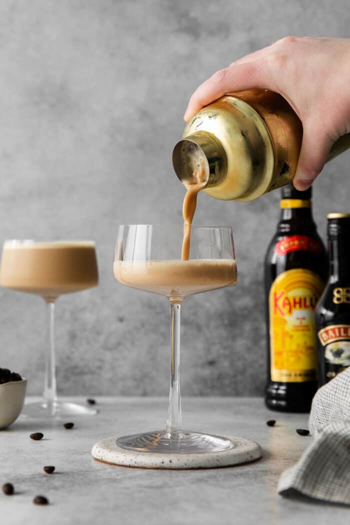 Made with espresso, vodka, and two liqueurs, this Espresso Martini is a strong coffee cocktail that's sure to provide an afternoon boost. Espresso martini being poured into an espresso glass