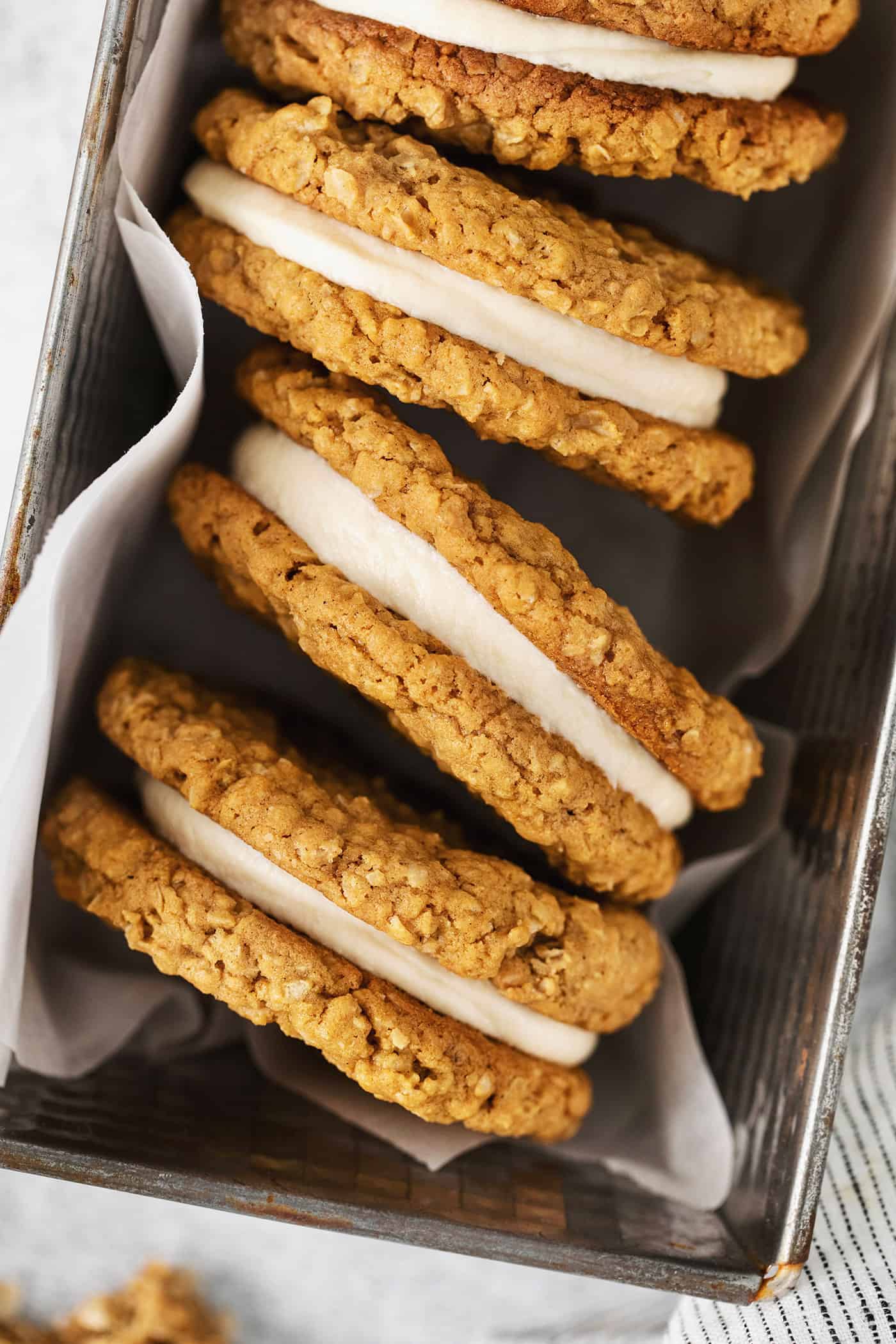 These Oatmeal Cream Pies are just like the classic store-bought variety, where a layer of sweet cream is sandwiched by chewy oatmeal cookies. Three oatmeal cream pie cookies on their side