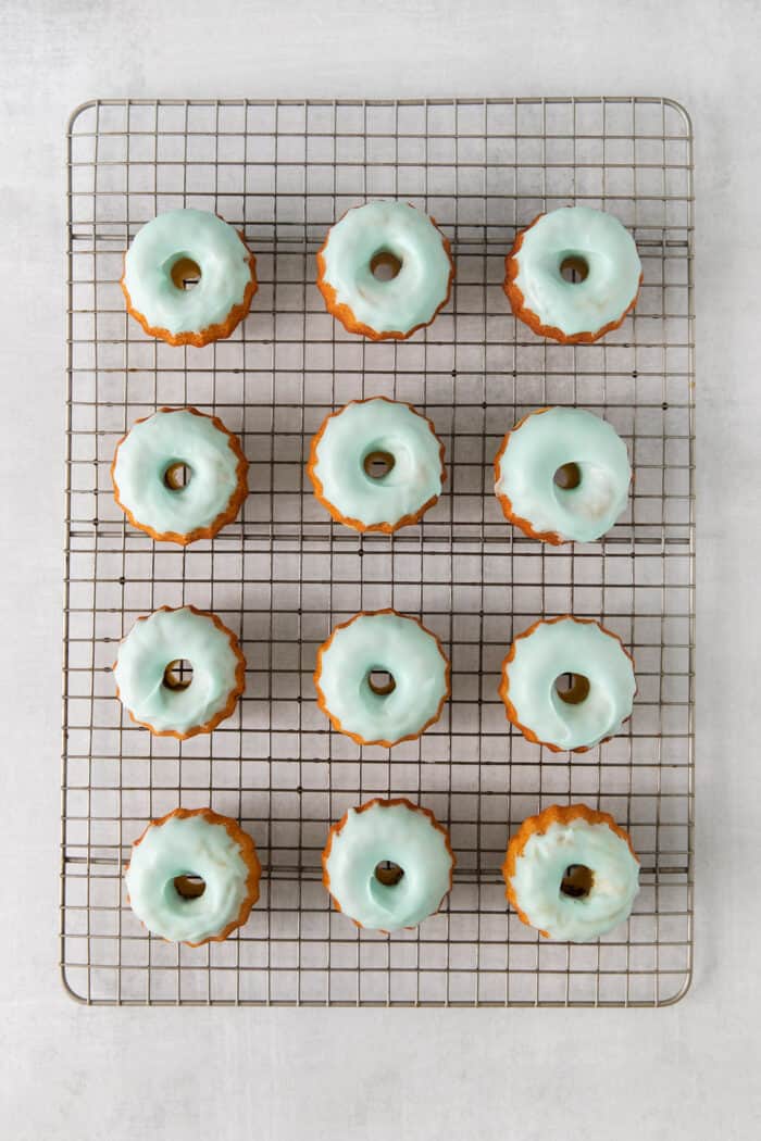 These Robin’s Egg Mini Bundt Cakes are the perfect sweet springtime treat. A moist, vanilla cake topped with a sweet glaze! Mini bundt cakes topped with blue icing on a cooling rack