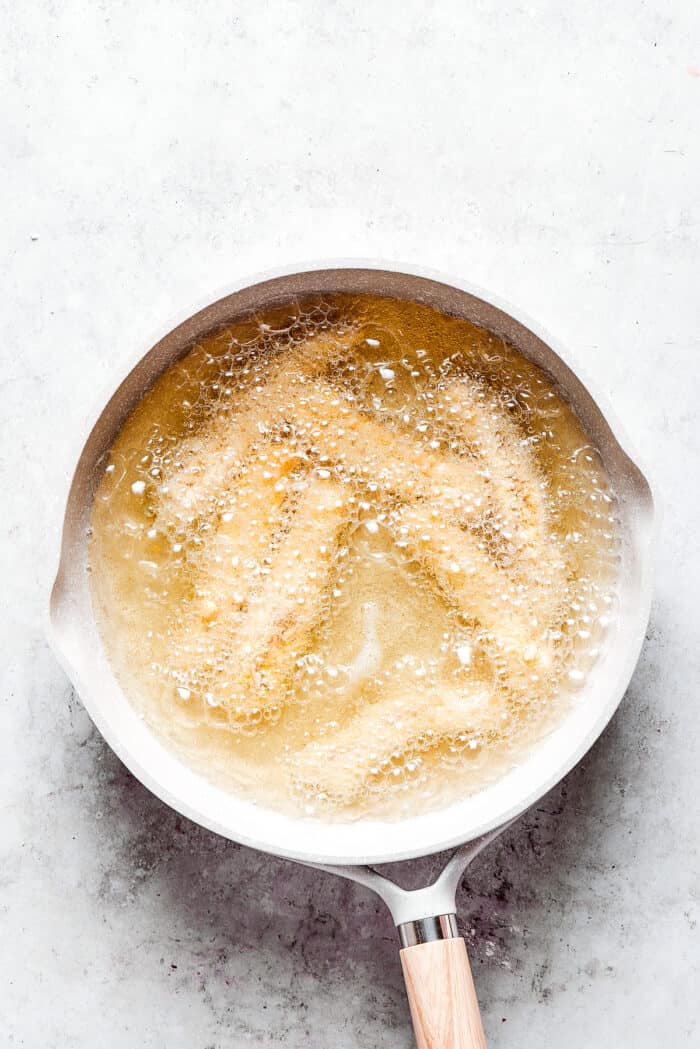 Made with thin, perfectly seasoned strips of chicken, these Chicken Fries are perfect dipped in this tangy roasted garlic aioli. Chicken fries frying in a skillet