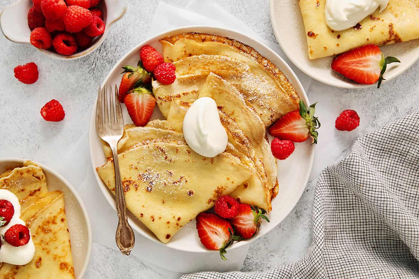 Make French crepes this Mother's Day and treat mom to an elegant, melt-in-your-mouth brunch dish with continental flair. A plate of French crepes topped with fruit on a table.