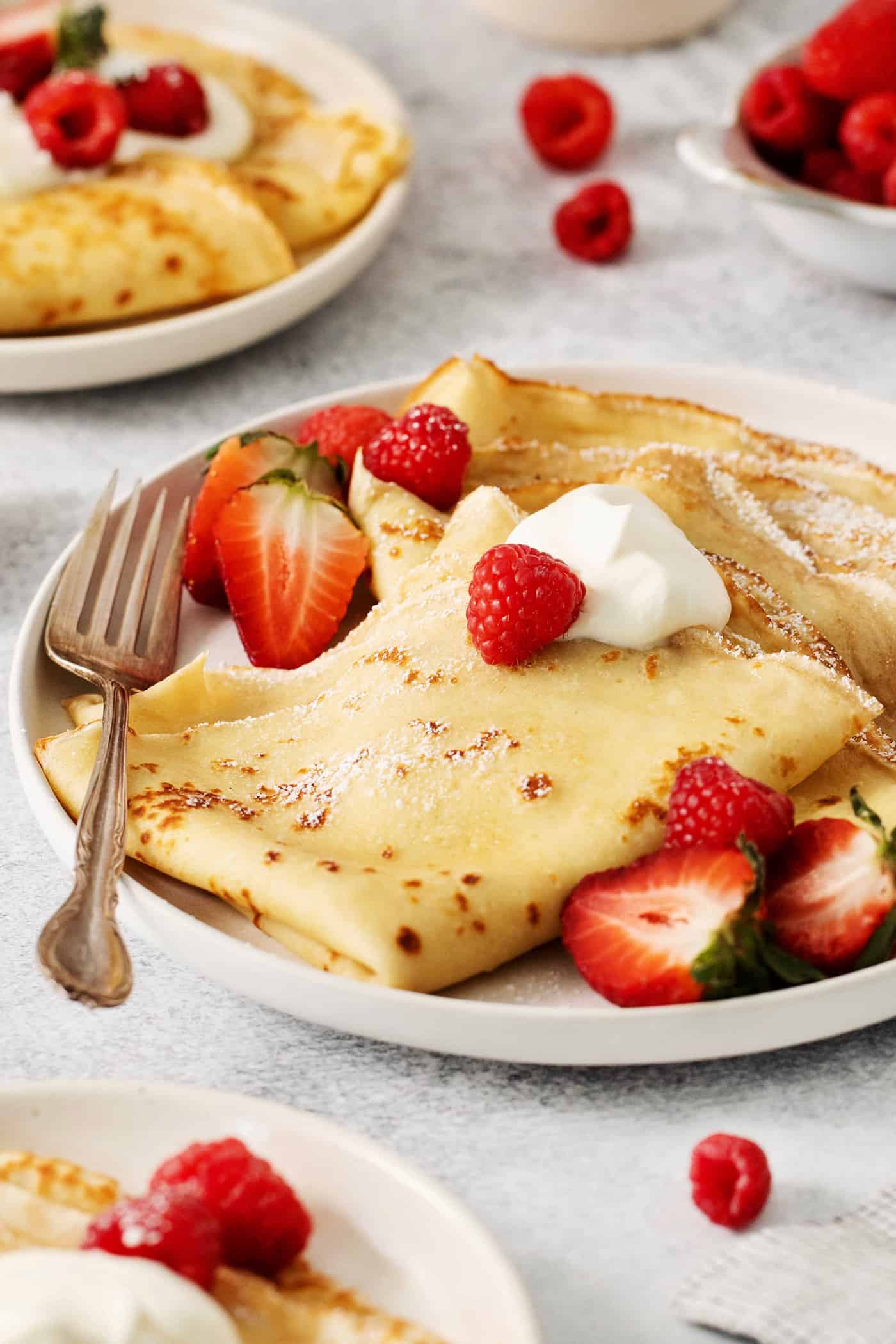 Make French crepes this Mother's Day and treat mom to an elegant, melt-in-your-mouth brunch dish with continental flair. A plate of French crepes topped with strawberries on a table.