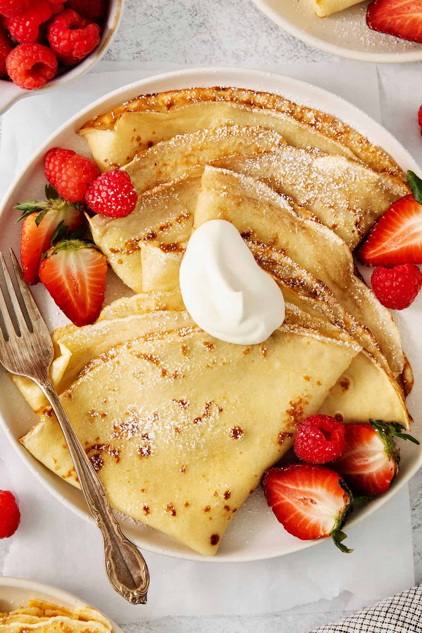 Make French crepes this Mother's Day and treat mom to an elegant, melt-in-your-mouth brunch dish with continental flair. A plate of French crepes topped with strawberries on a table.