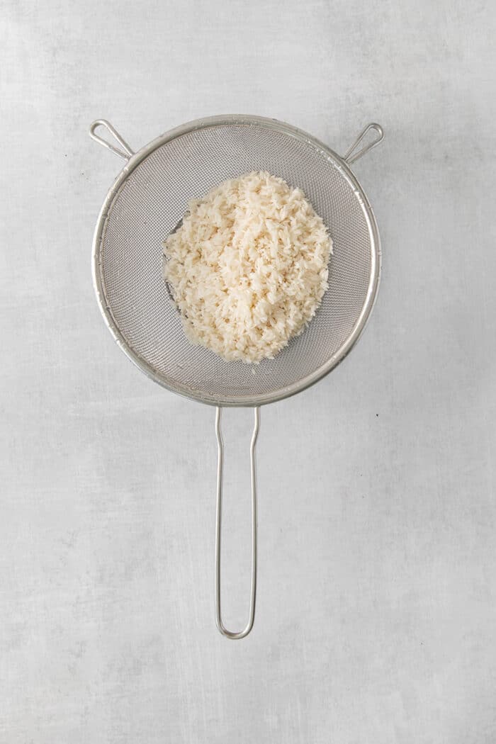 Cilantro Lime Rice is the perfect base or side for so many recipes. The rice is perfectly cooked and seasoned with hints of lime & cilantro. Rice in a mesh strainer