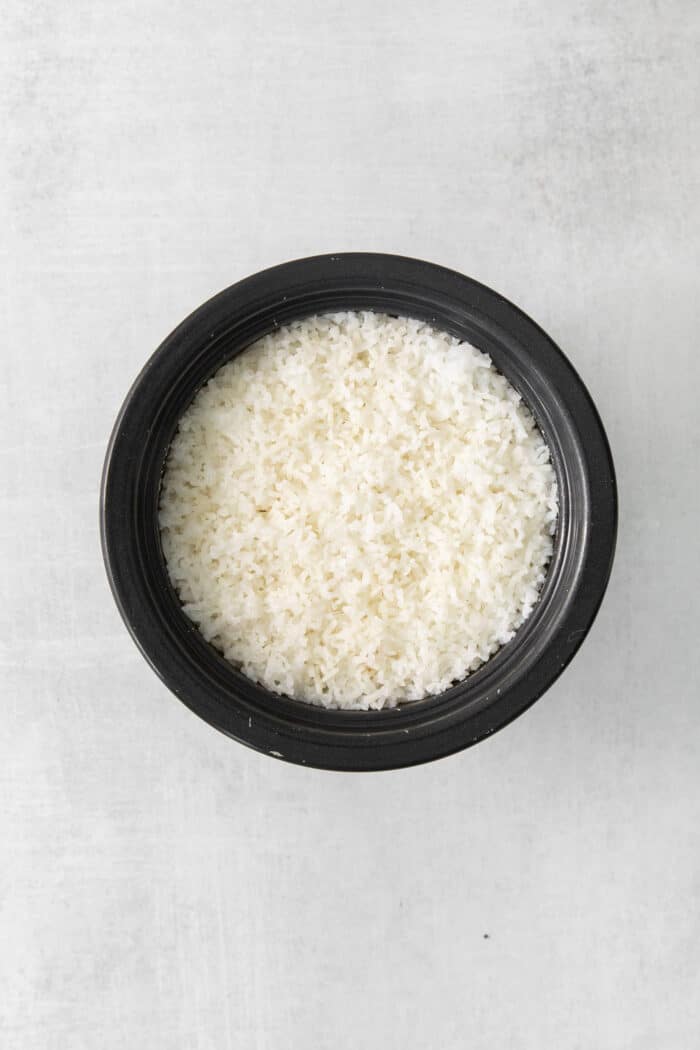Cilantro Lime Rice is the perfect base or side for so many recipes. The rice is perfectly cooked and seasoned with hints of lime & cilantro. Cooked white rice in a black bowl