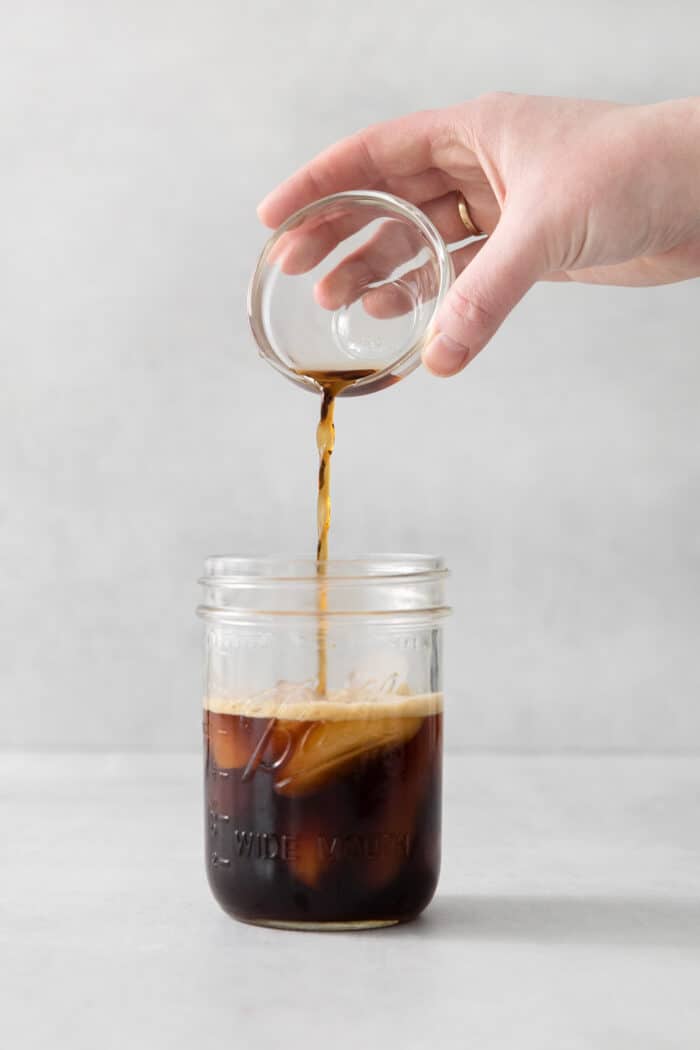 Made with just 4 ingredients, this Iced Brown Sugar Oatmilk Shaken Espresso tastes just like the Starbucks version! Brown sugar syrup being added to a jar with espresso and ice
