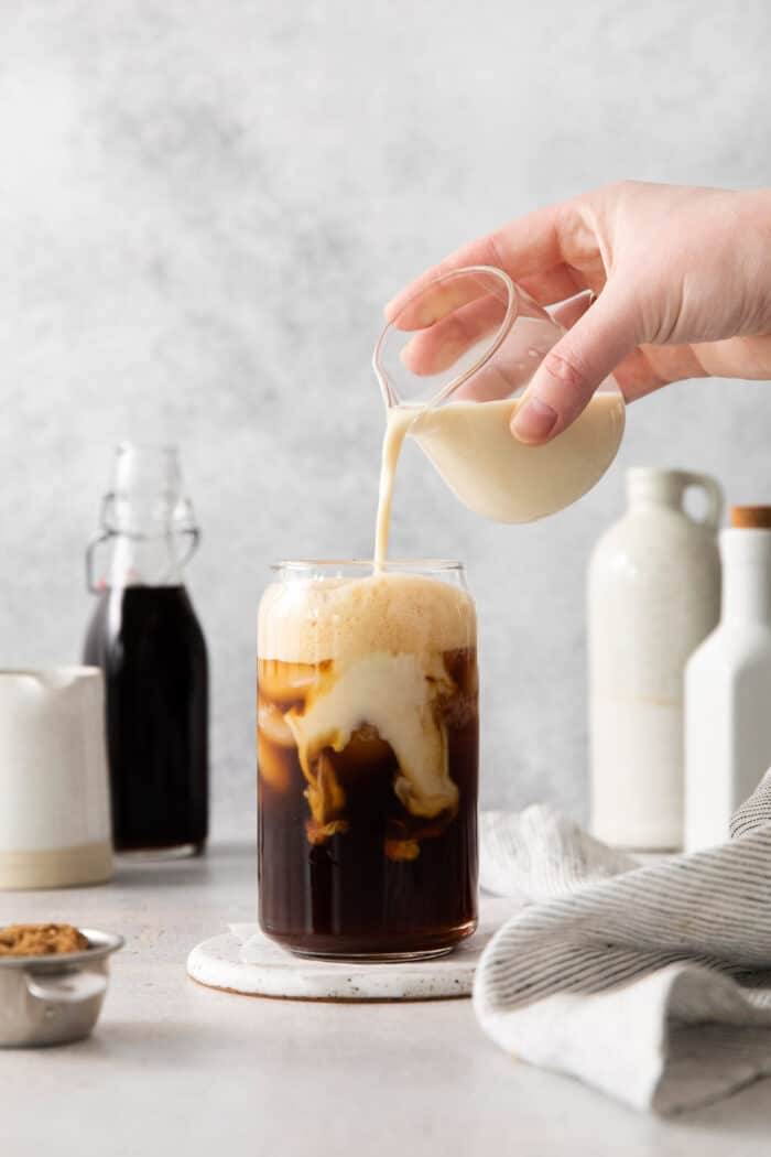Made with just 4 ingredients, this Iced Brown Sugar Oatmilk Shaken Espresso tastes just like the Starbucks version! Oatmilk being poured into a glass with espresso