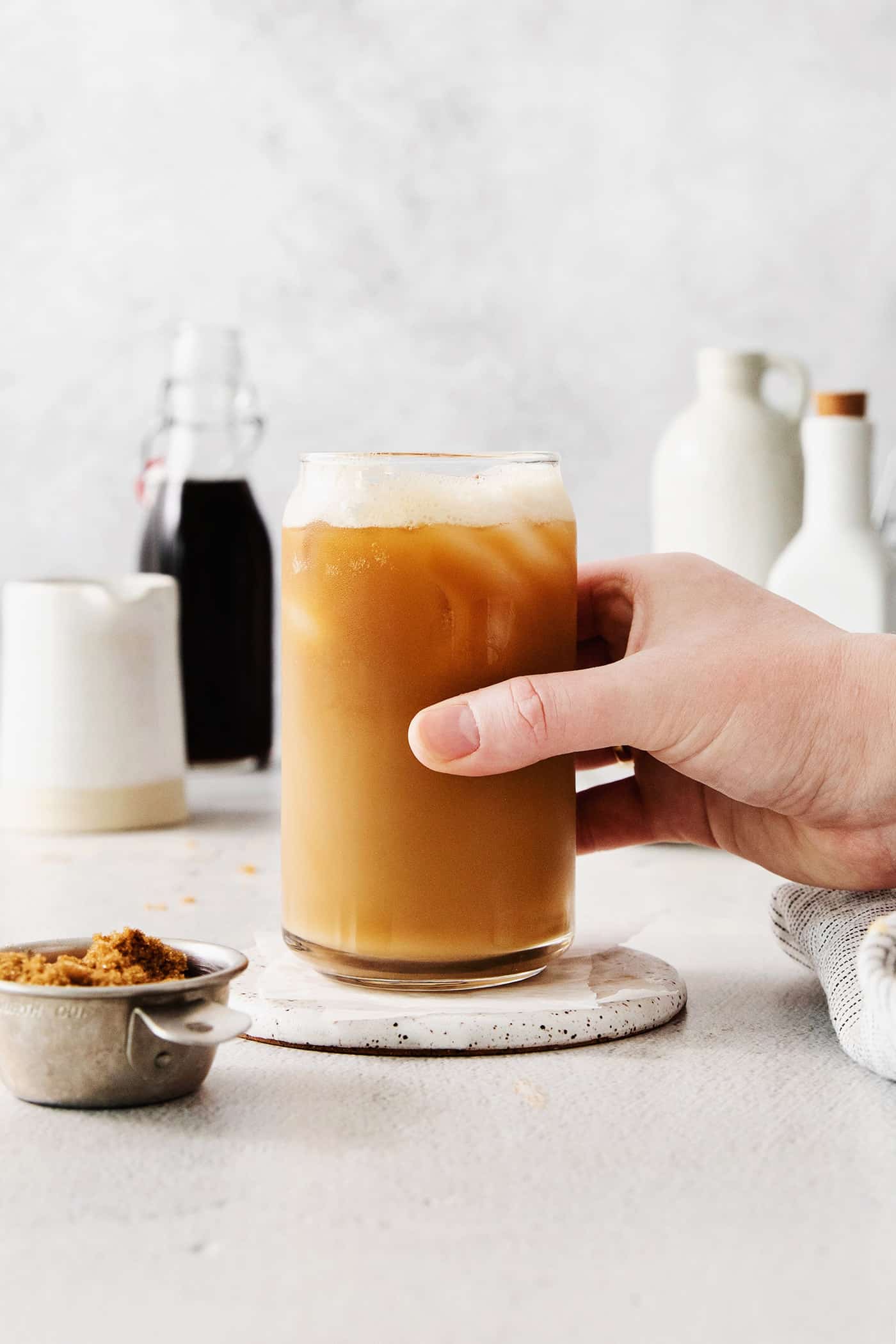 Made with just 4 ingredients, this Iced Brown Sugar Oatmilk Shaken Espresso tastes just like the Starbucks version! A hand grabbing an iced brown sugar oatmilk shaken espresso