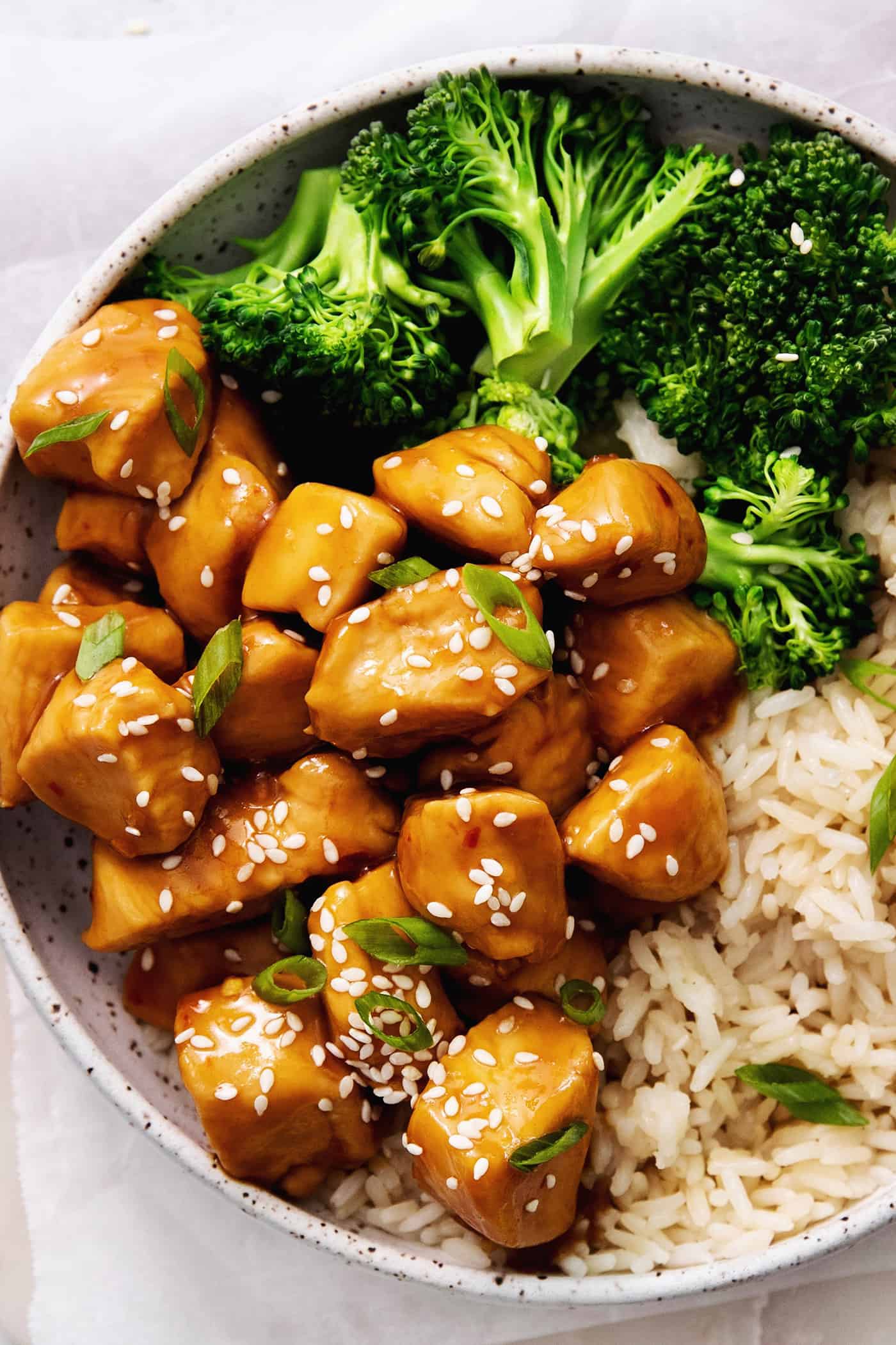 Inspired by Chinese takeout, this Mandarin Chicken is tender and juicy, coated in a sweet and sticky sauce. Ready in 30 minutes! A plate of mandarin orange chicken with rice and broccoli