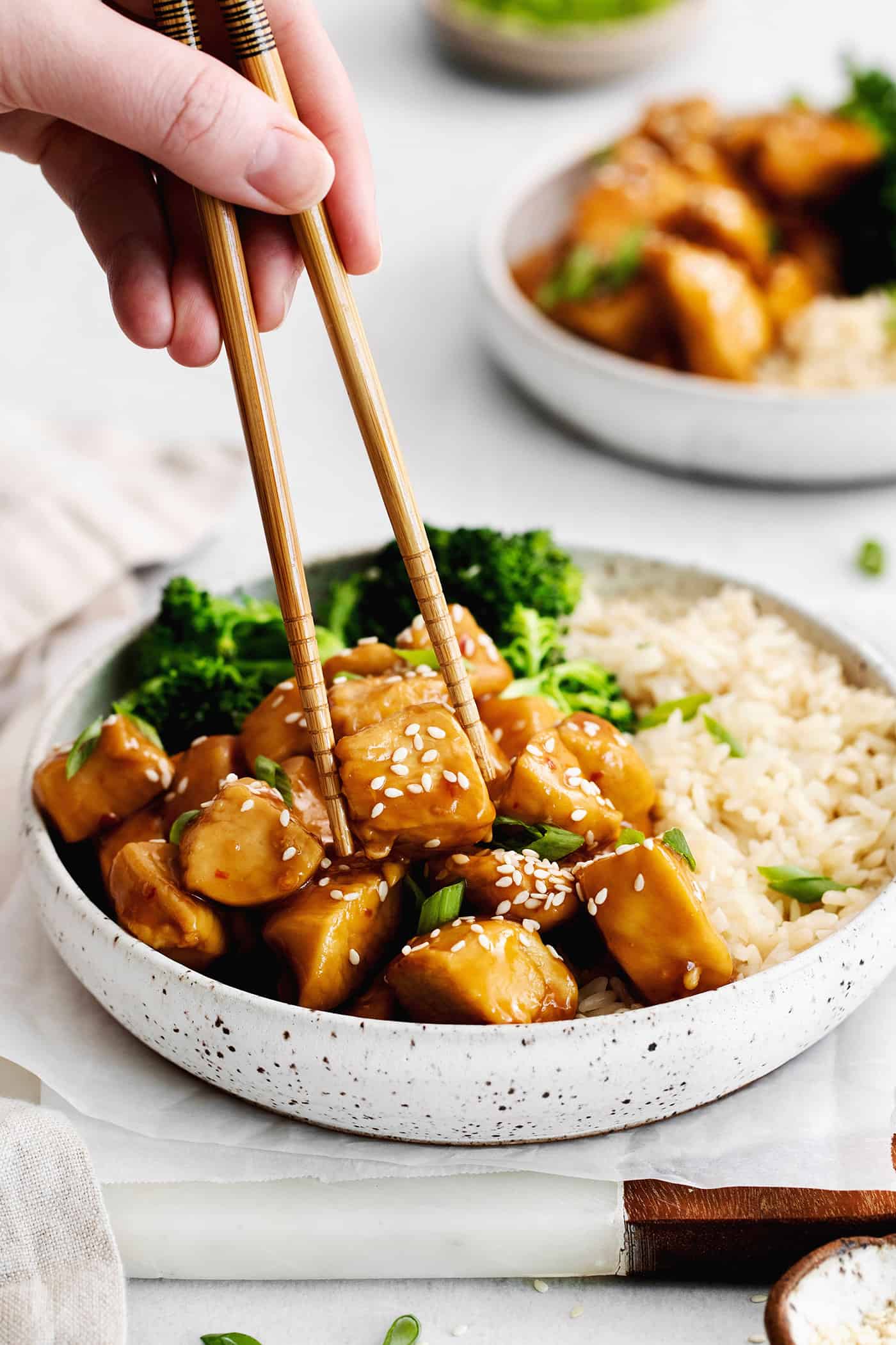 Inspired by Chinese takeout, this Mandarin Chicken is tender and juicy, coated in a sweet and sticky sauce. Ready in 30 minutes! Chopsticks grabbing a piece of mandarin chicken