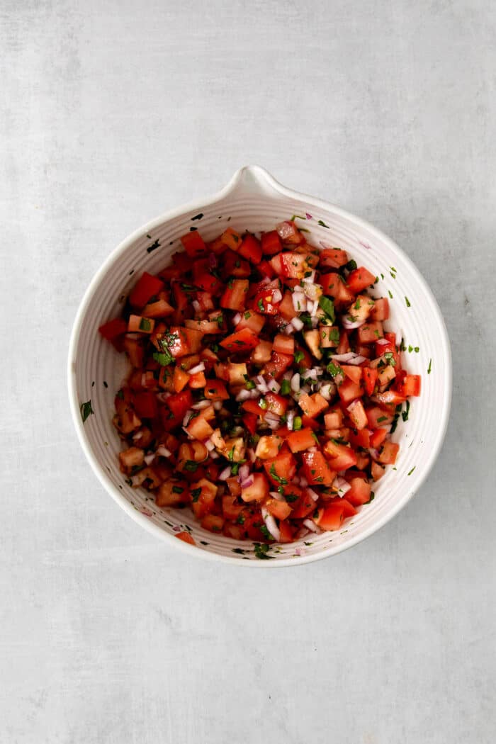 Made with ripe tomatoes, red onion, and lime juice, Homemade Pico de Gallo is the perfect garnish for anything from tacos to scallop bowls! Pico de gallo ingredients mixed in a bowl