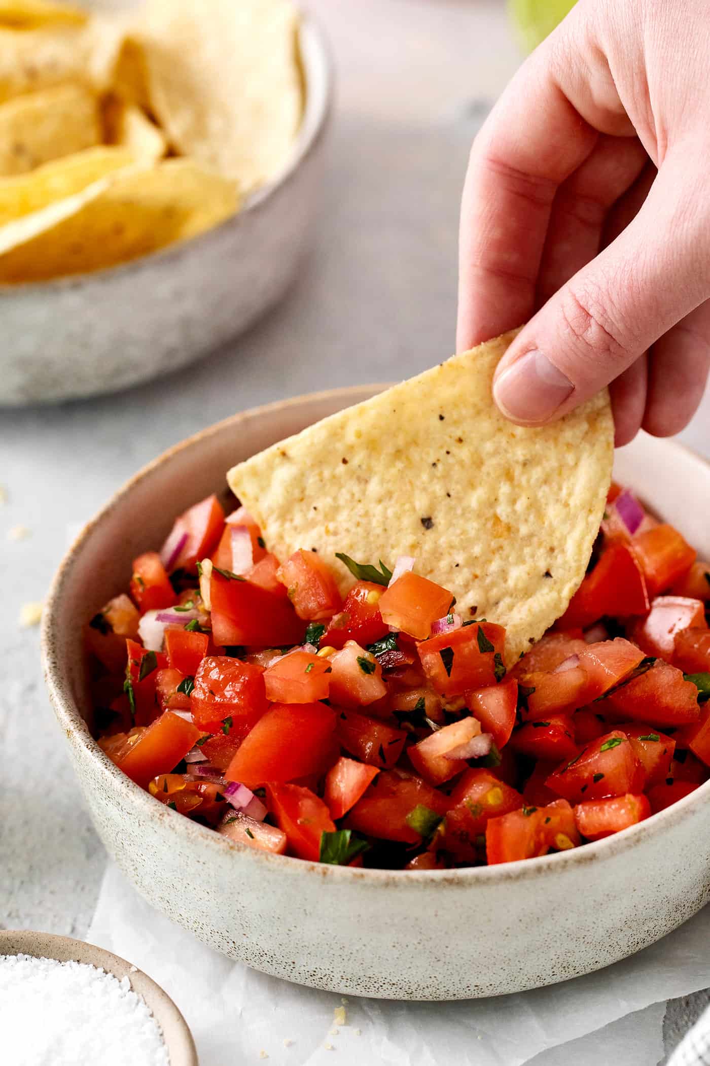 Made with ripe tomatoes, red onion, and lime juice, Homemade Pico de Gallo is the perfect garnish for anything from tacos to scallop bowls! A chip being dipped into pico de gallo