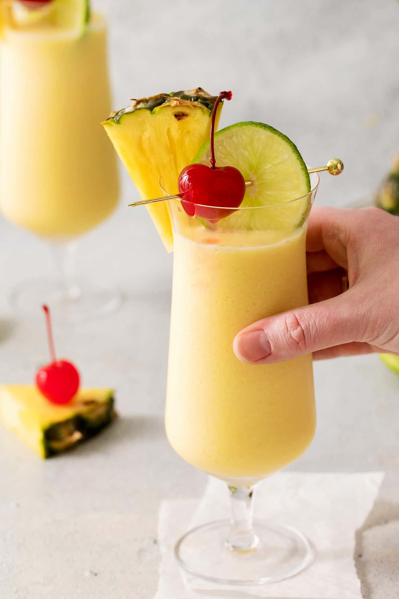 This Classic Pina Colada is fruity and refreshing, with sweet pineapple, a hint of lime, and plenty of rum. The perfect cocktail for summer! A hand grabbing a pina colada drink