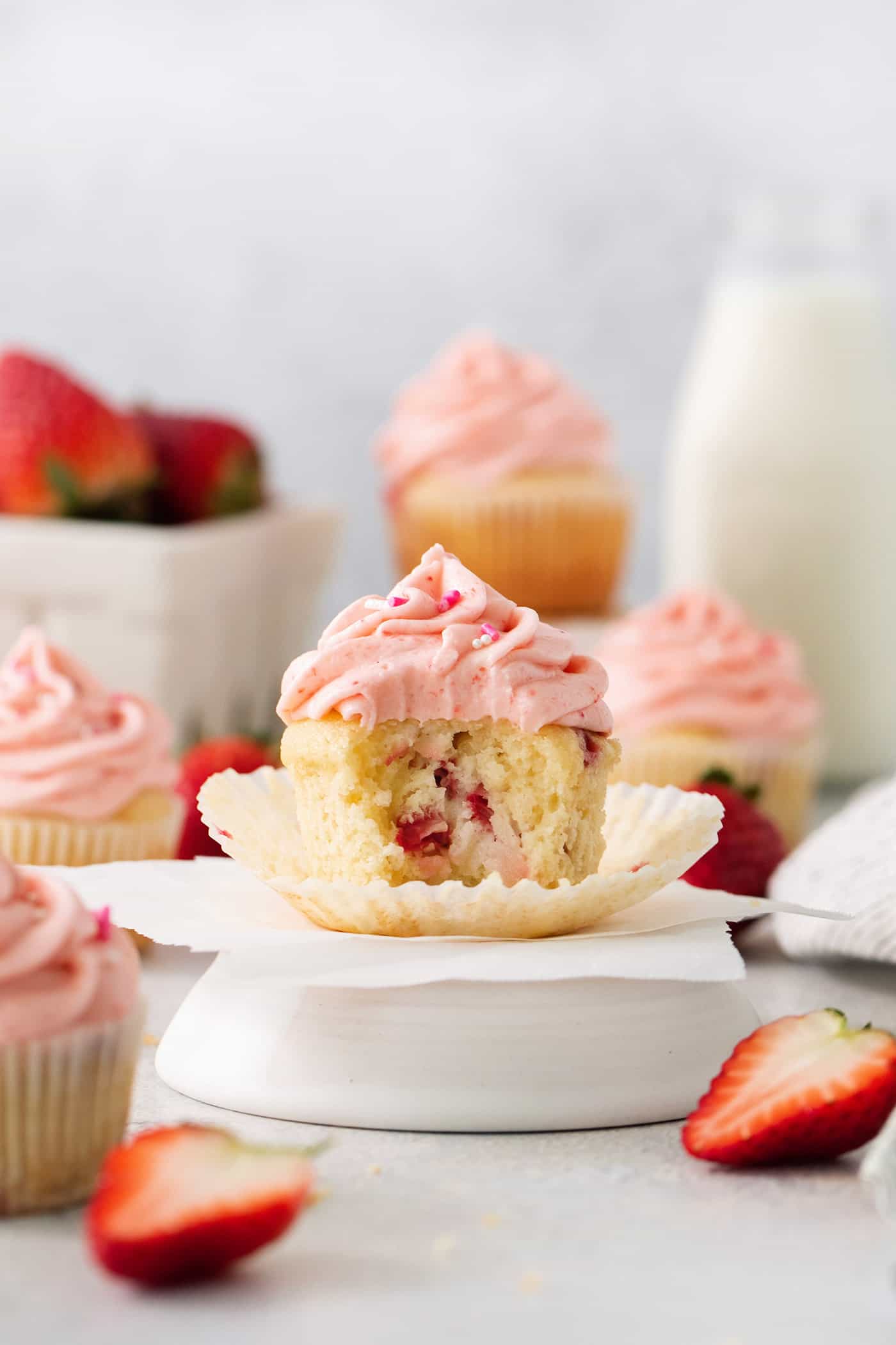 Vibrantly pink Strawberry Cupcakes will dress up your Mother's Day table - or make them anytime for a special strawberry treat. A batch of frosted strawberry cupcakes is shown with one cupcake cut open to show the interior.