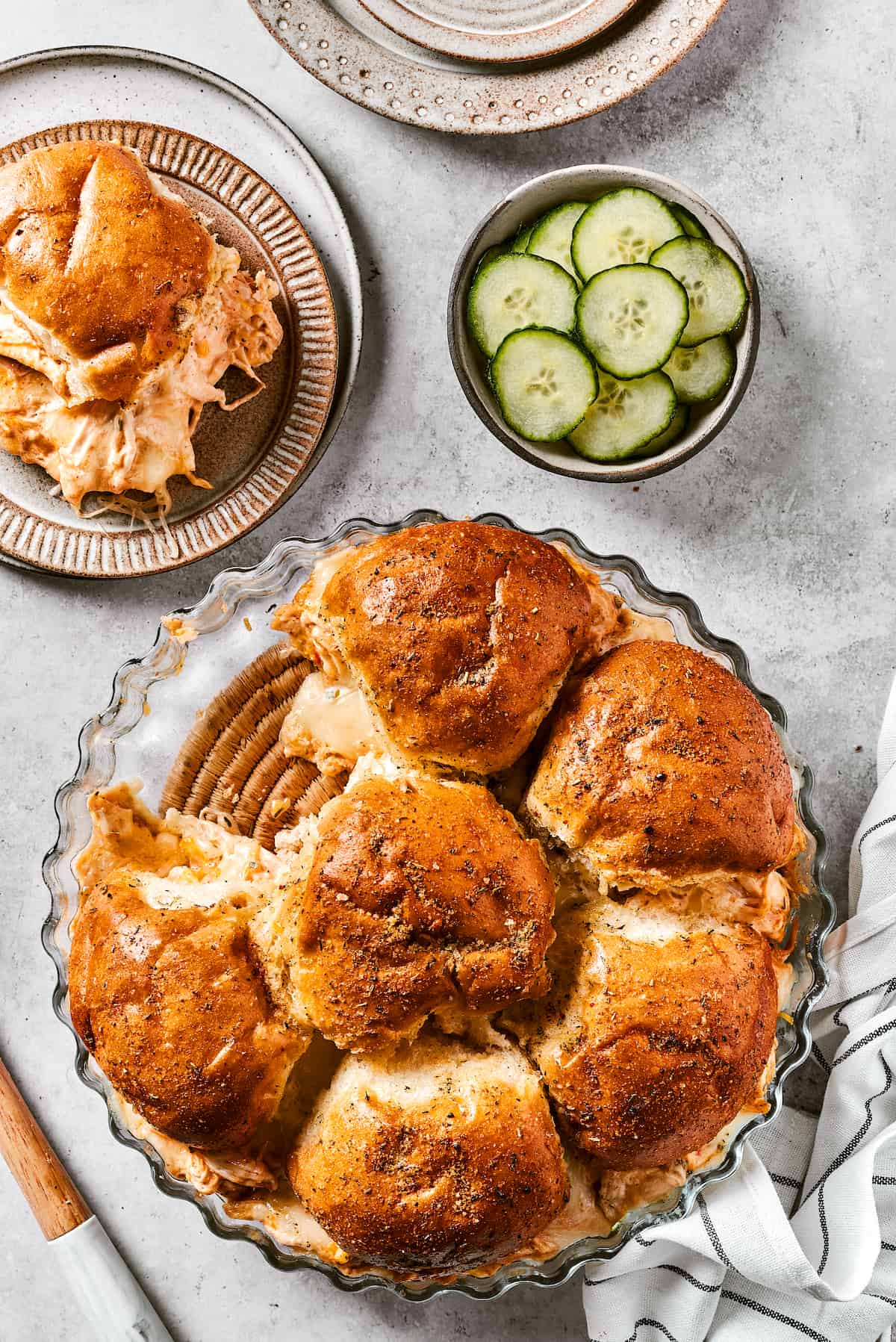 Buffalo Chicken Sliders are hand-held bites of spicy goodness! Loaded with melted cheese and creamy ranch, these are sure to be a hit. Buffalo chicken sliders are shown on plates with more sliders ready to serve.