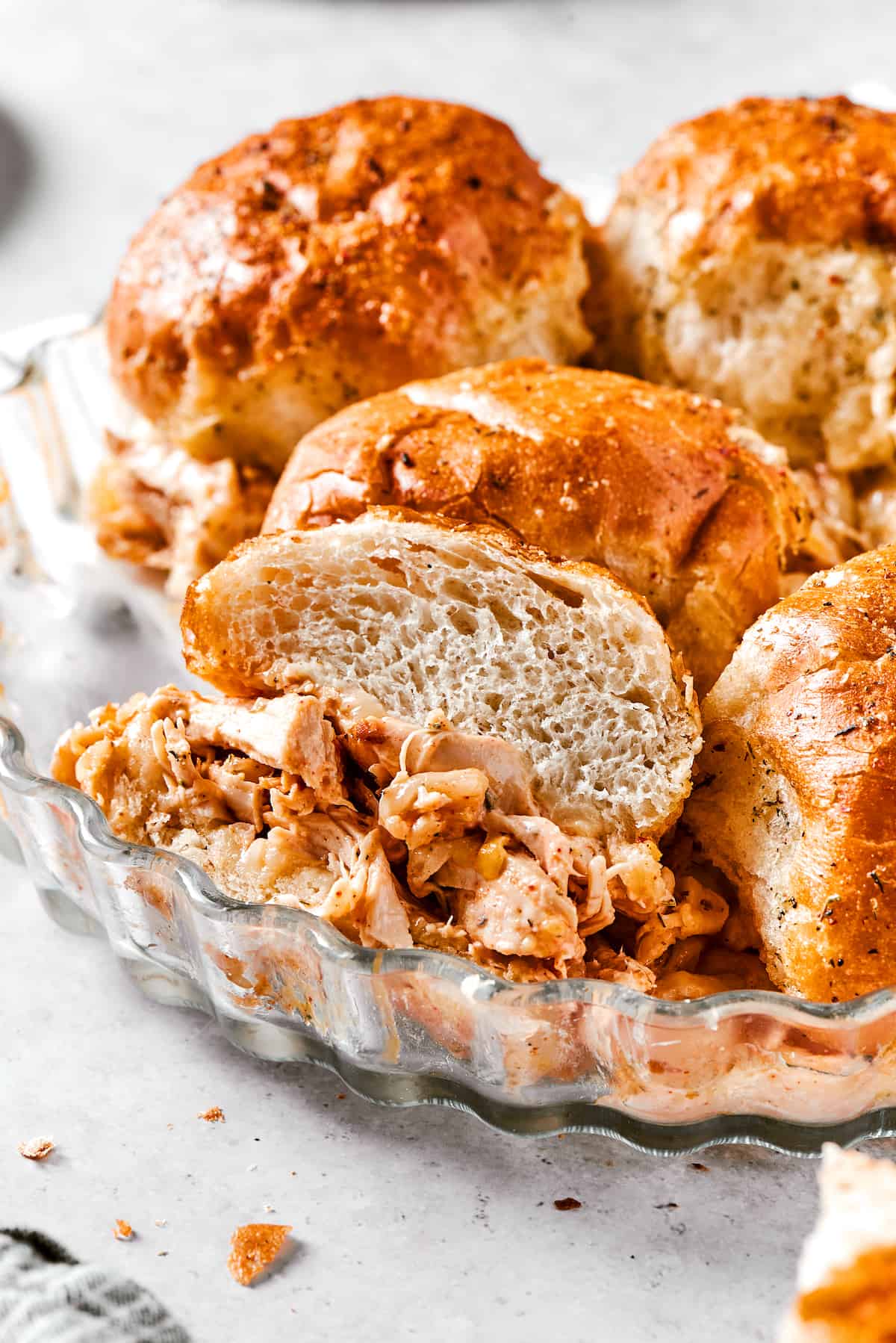 Buffalo Chicken Sliders are hand-held bites of spicy goodness! Loaded with melted cheese and creamy ranch, these are sure to be a hit. Buffalo chicken sliders are shown in a metal dish.