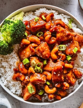 Chinese cashew chicken with rice and broccoli in a white bowl